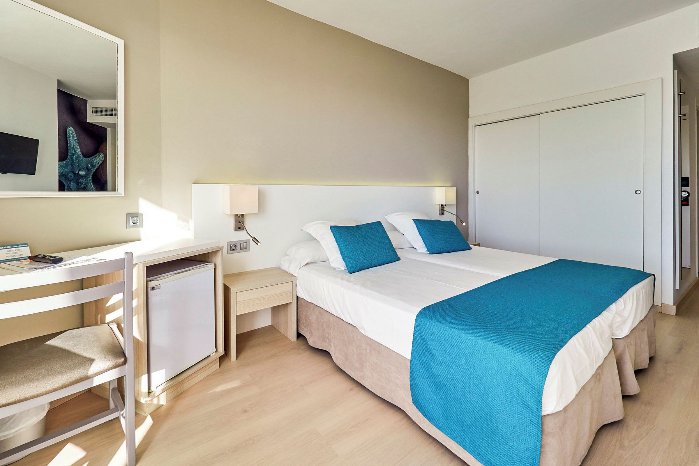 Ett hotellrum med två enkelsängar, vita sängkläder och blå överkast. (AI-genererad text)