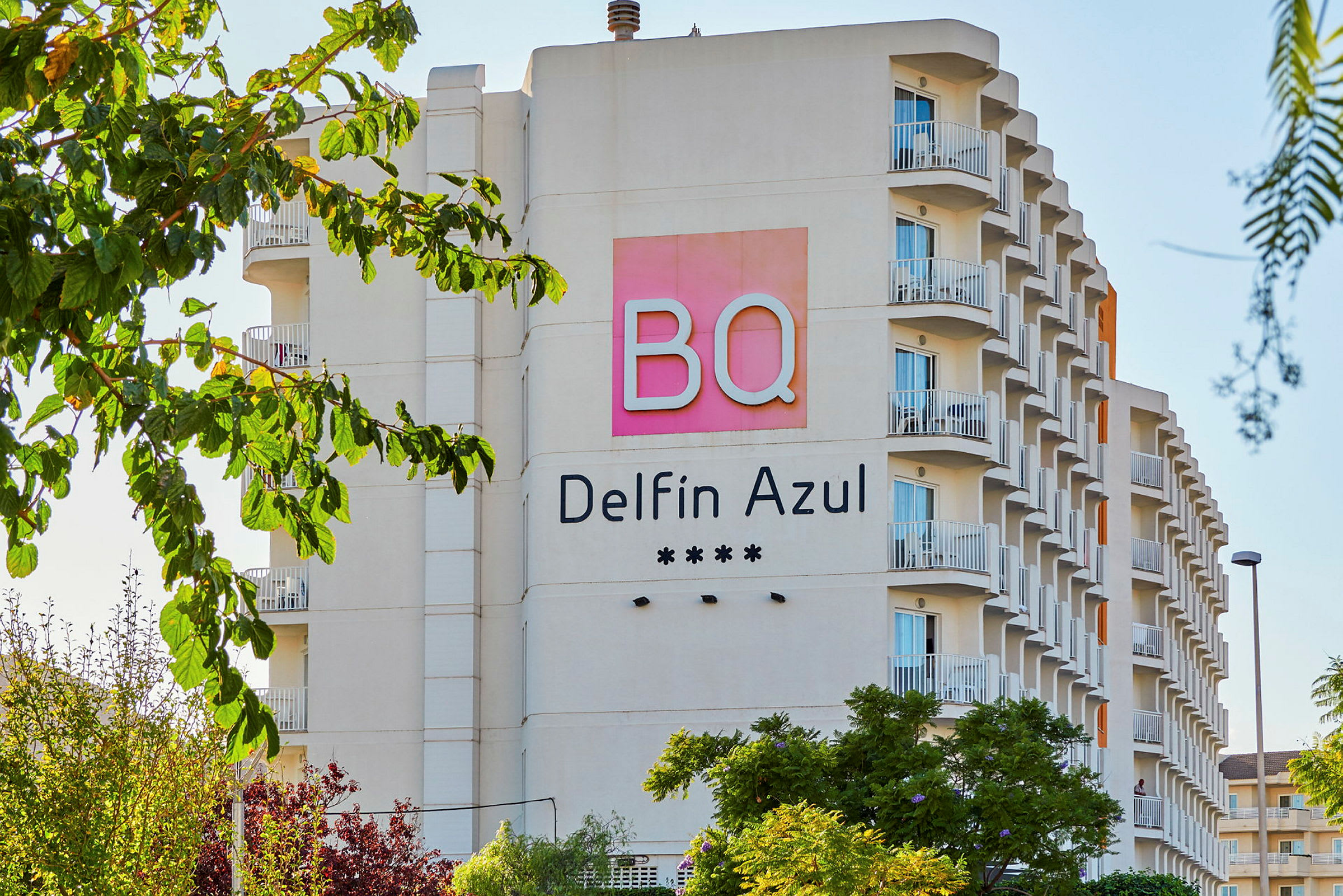 Hotellfasad med namnet BQ Delfin Azul och fyra stjärnor, omgivna av träd. (AI-genererad text)