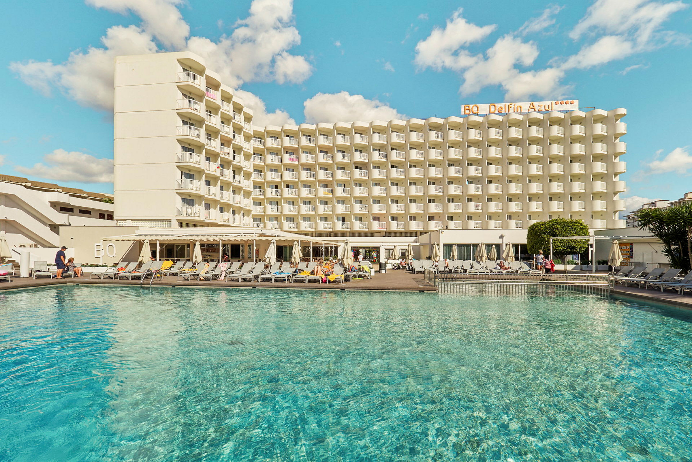 Bild av en hotellbyggnad med en pool i förgrunden. (AI-genererad text)