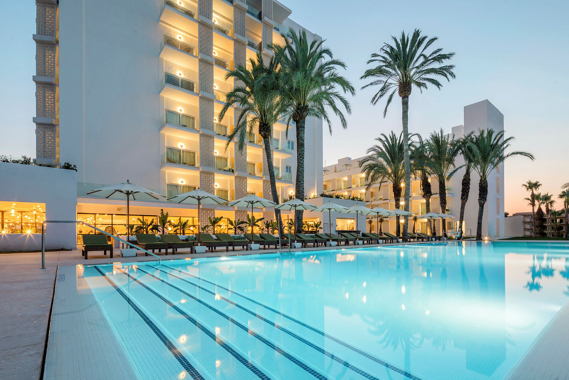 Hotell med pool och solstolar omgivna av palmer. (AI-genererad text)
