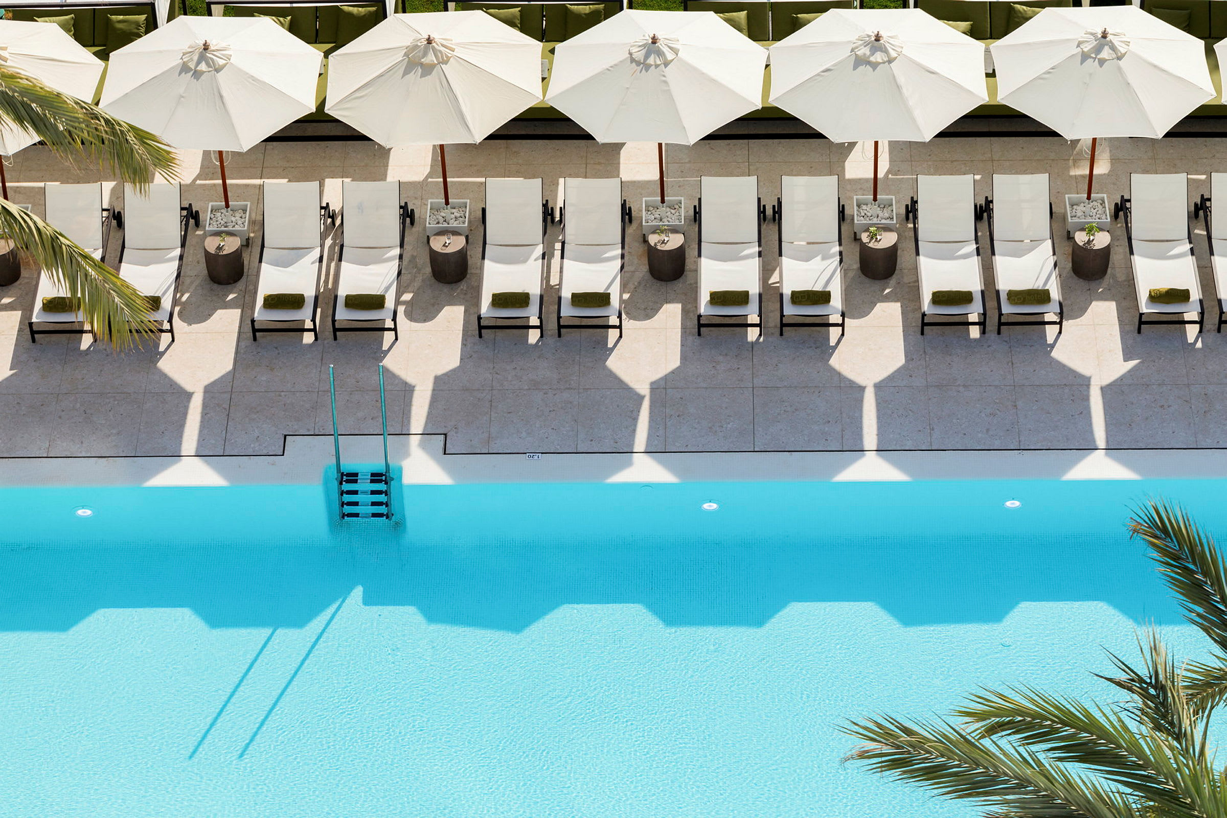 Solstolar och parasoll på en poolterrass vid en blå pool. (AI-genererad text)