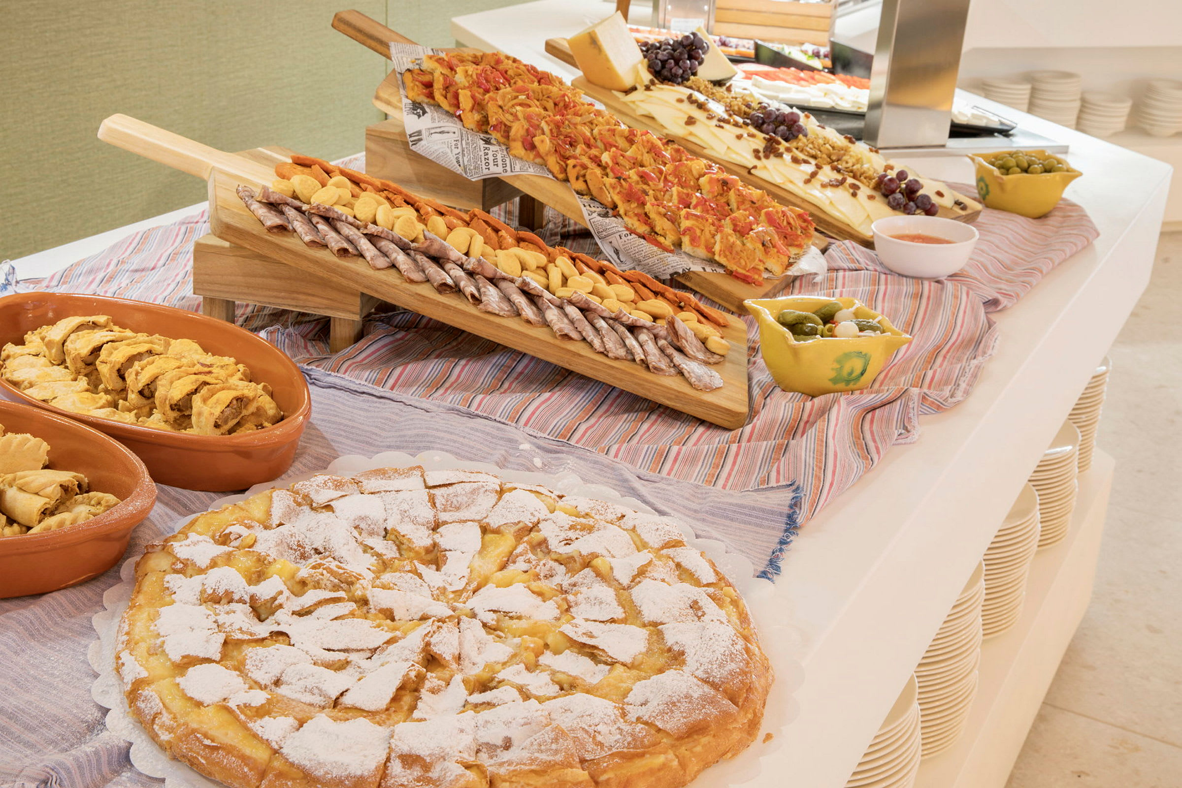 Ett upplägg med olika maträtter inklusive bakverk, bröd, ansjovis, ostar och oliver. (AI-genererad text)