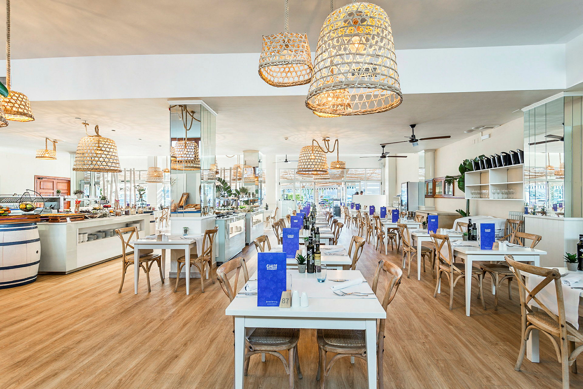 Restaurang med vita bord och trästolar, dekorerad med hängande flätade lampor. (AI-genererad text)