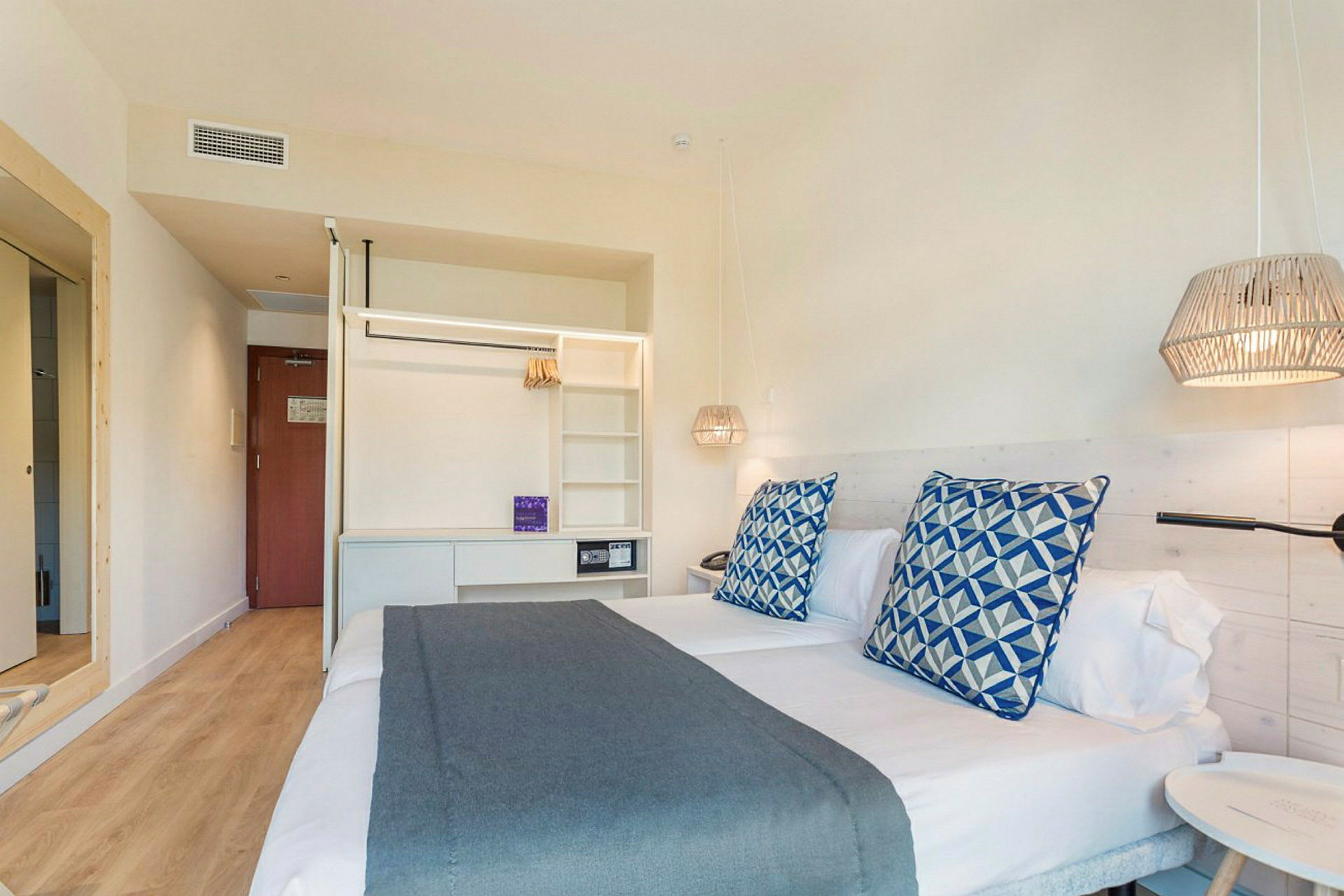 Interiör av ett hotellrum med två enkelsängar, dekorativa kuddar och sänglampor. (AI-genererad text)