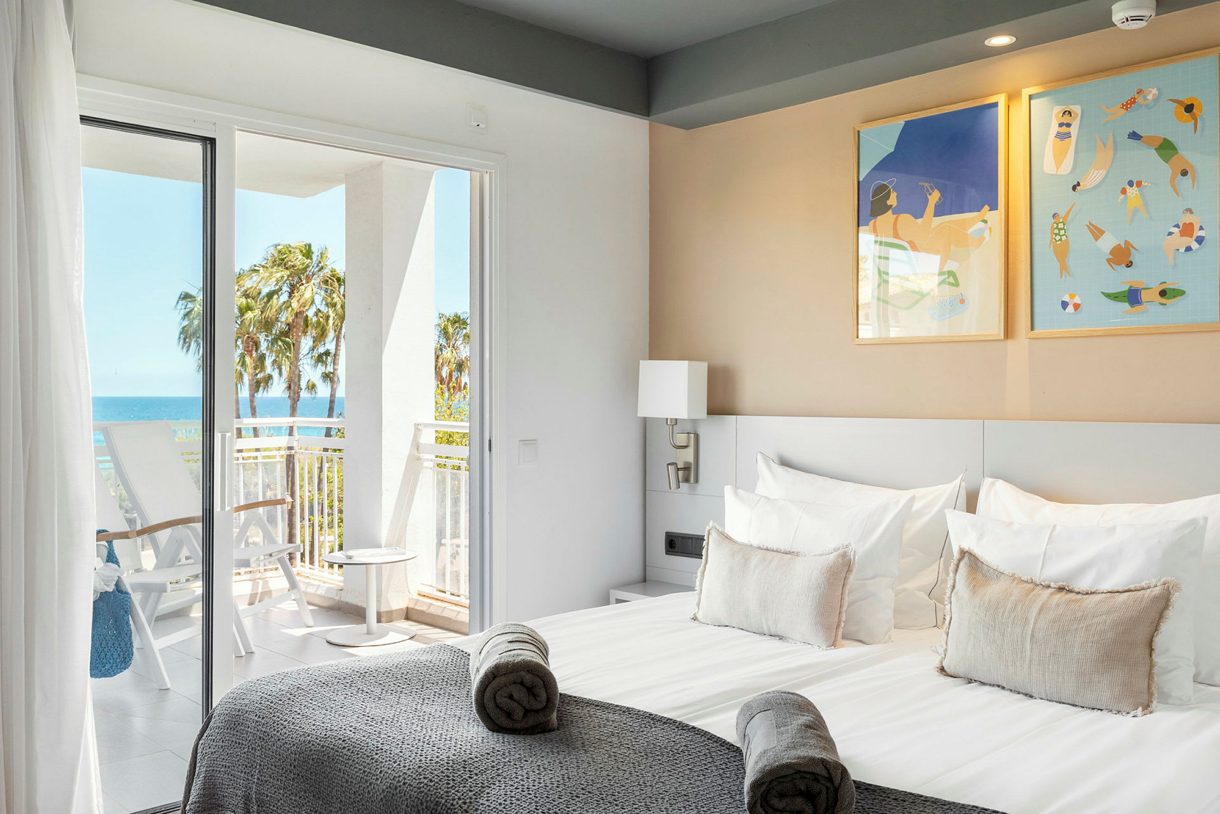 Hotellrum med en dubbelsäng, balkongdörrar och vy ut mot havet. (AI-genererad text)