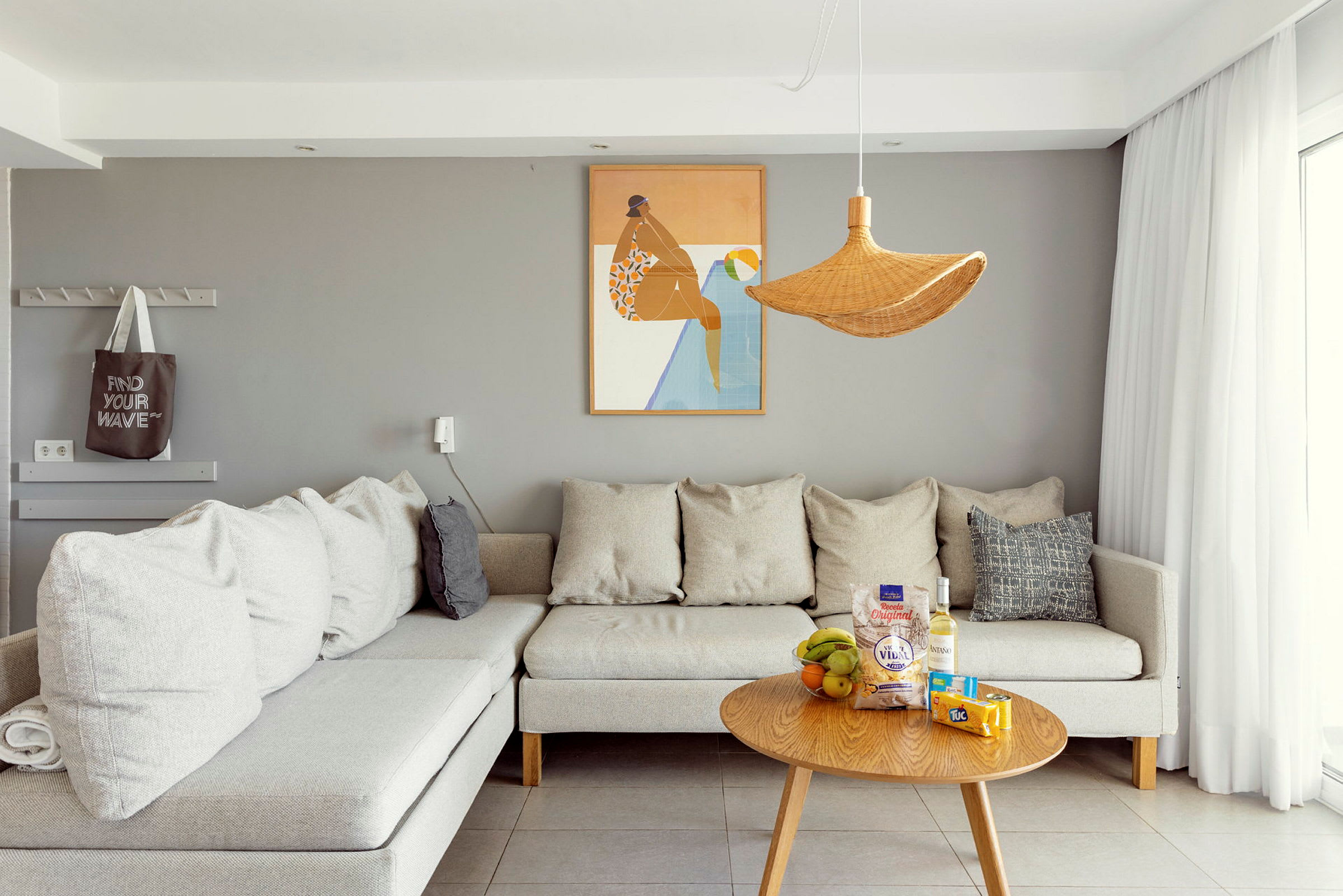 Bild på ett modernt vardagsrum med en grå vägg, grå soffa och ett träbord med snacks och dryck. (AI-genererad text)
