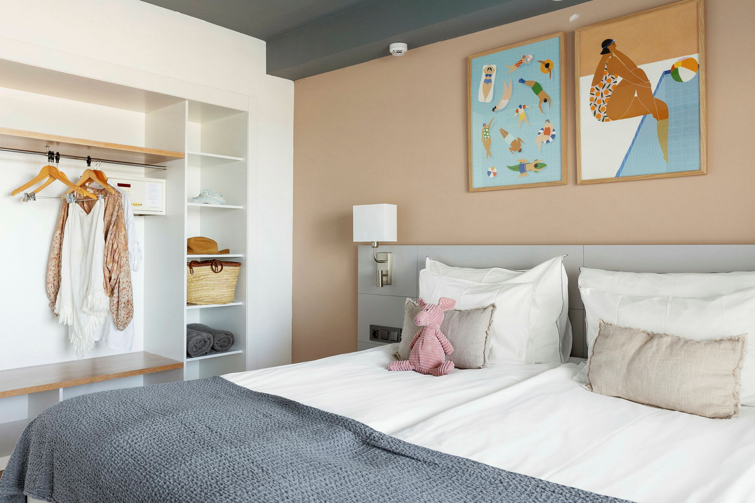 Ett hotellrum med en säng, väggkonst och en hylla. (AI-genererad text)