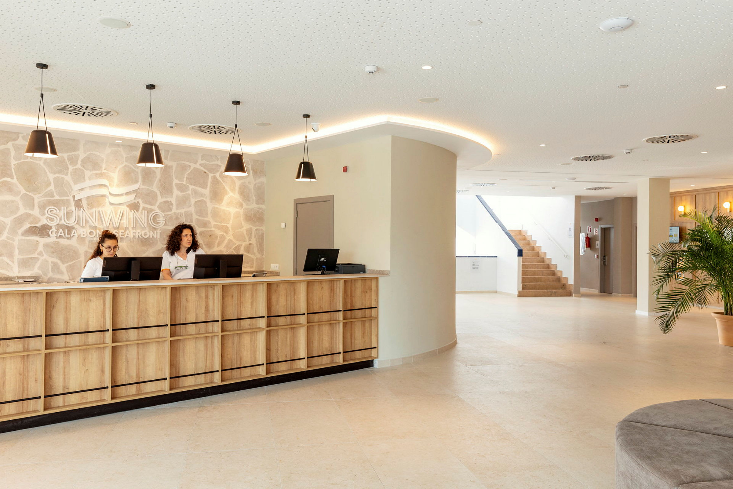 Receptionen på Sunwing Cala Bona Seafront med träpaneler och en stenvägg. (AI-genererad text)