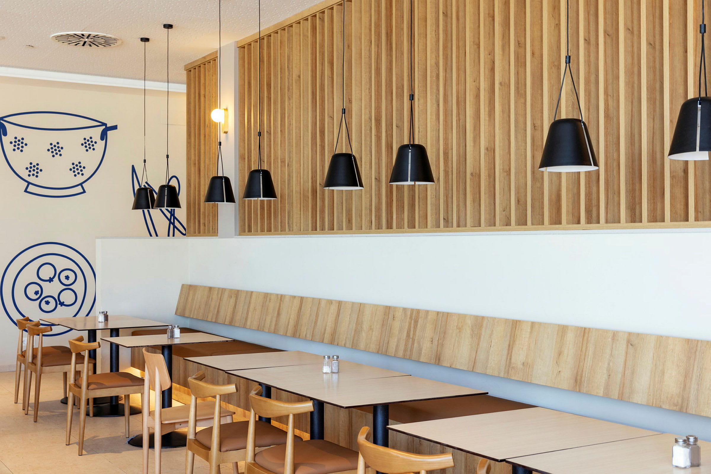 En modern restaurang med träpaneler och svarta hänglampor. (AI-genererad text)