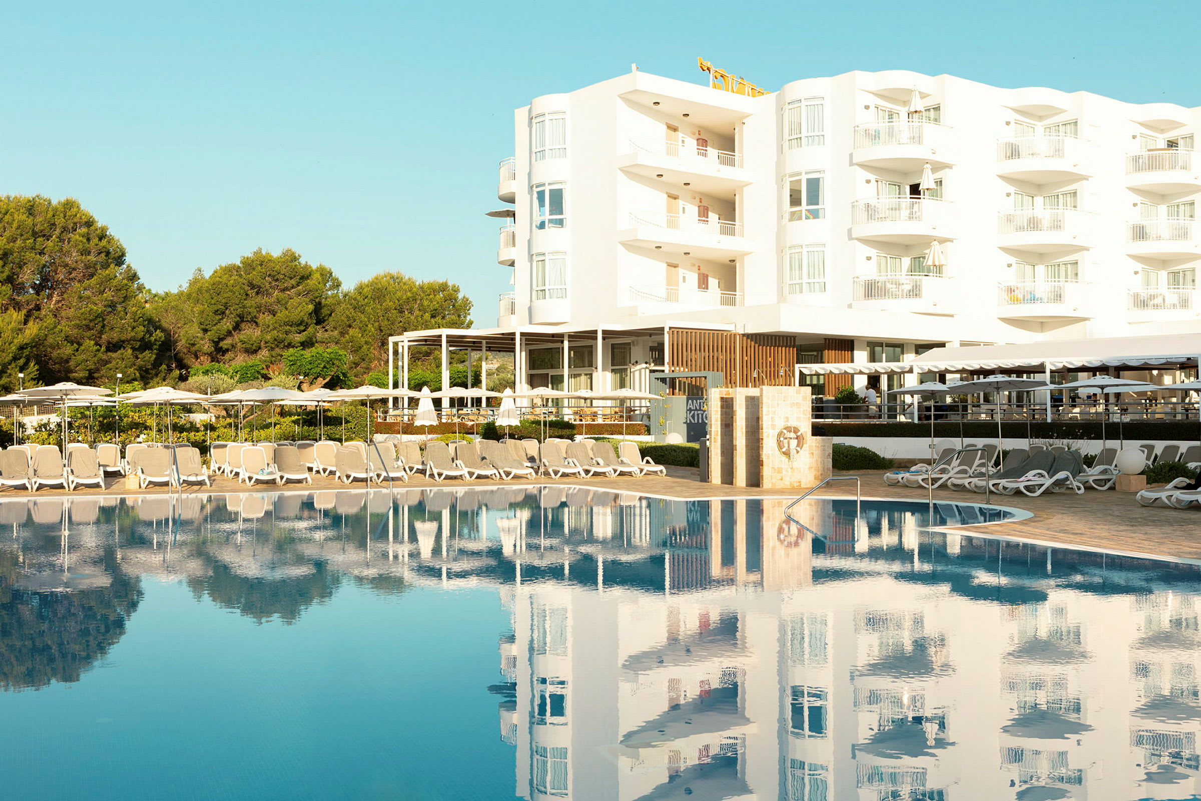 Solbäddar och parasoller vid en pool framför ett hotell. (AI-genererad text)