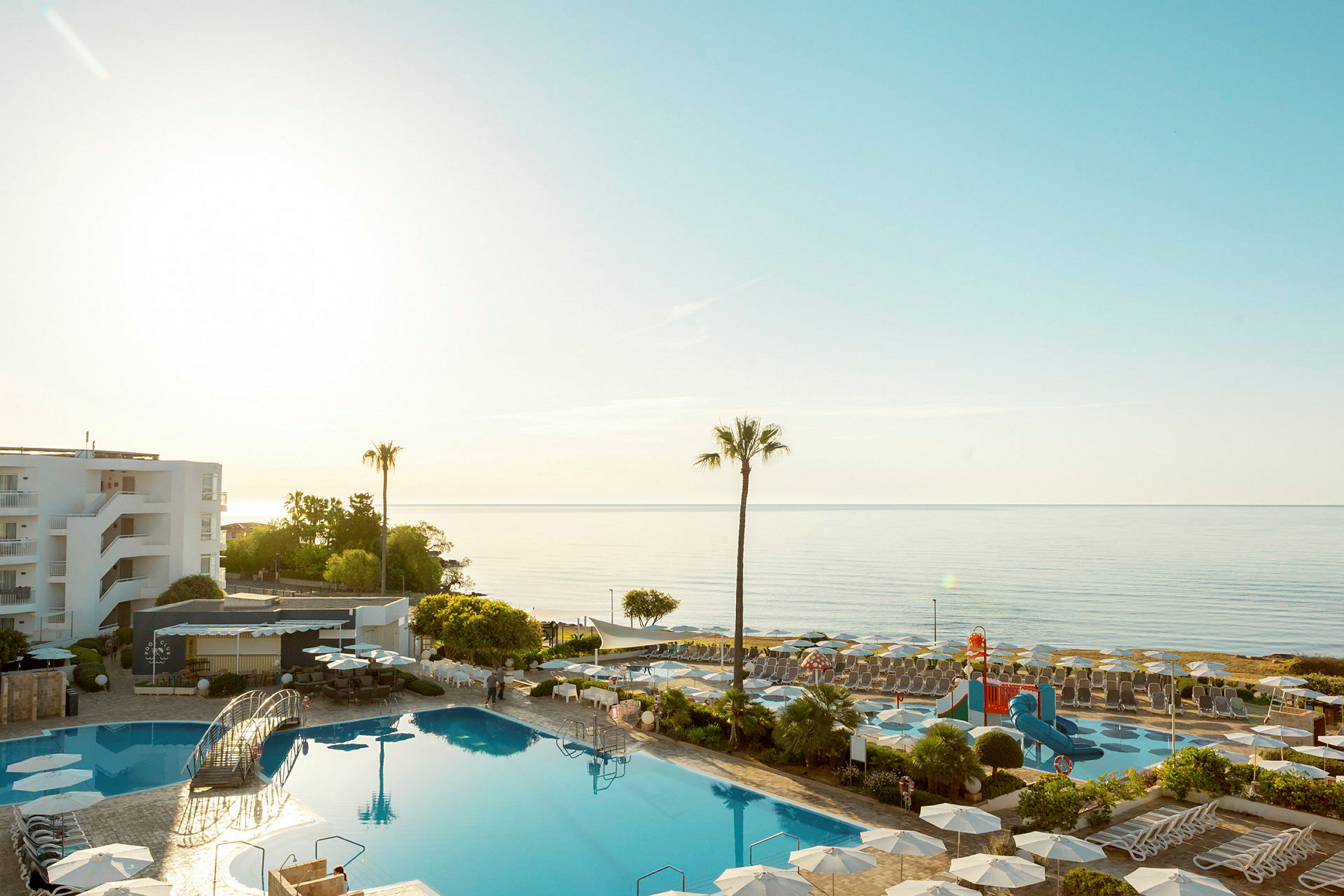 En solbelyst resort med swimmingpool och utsikt över havet. (AI-genererad text)