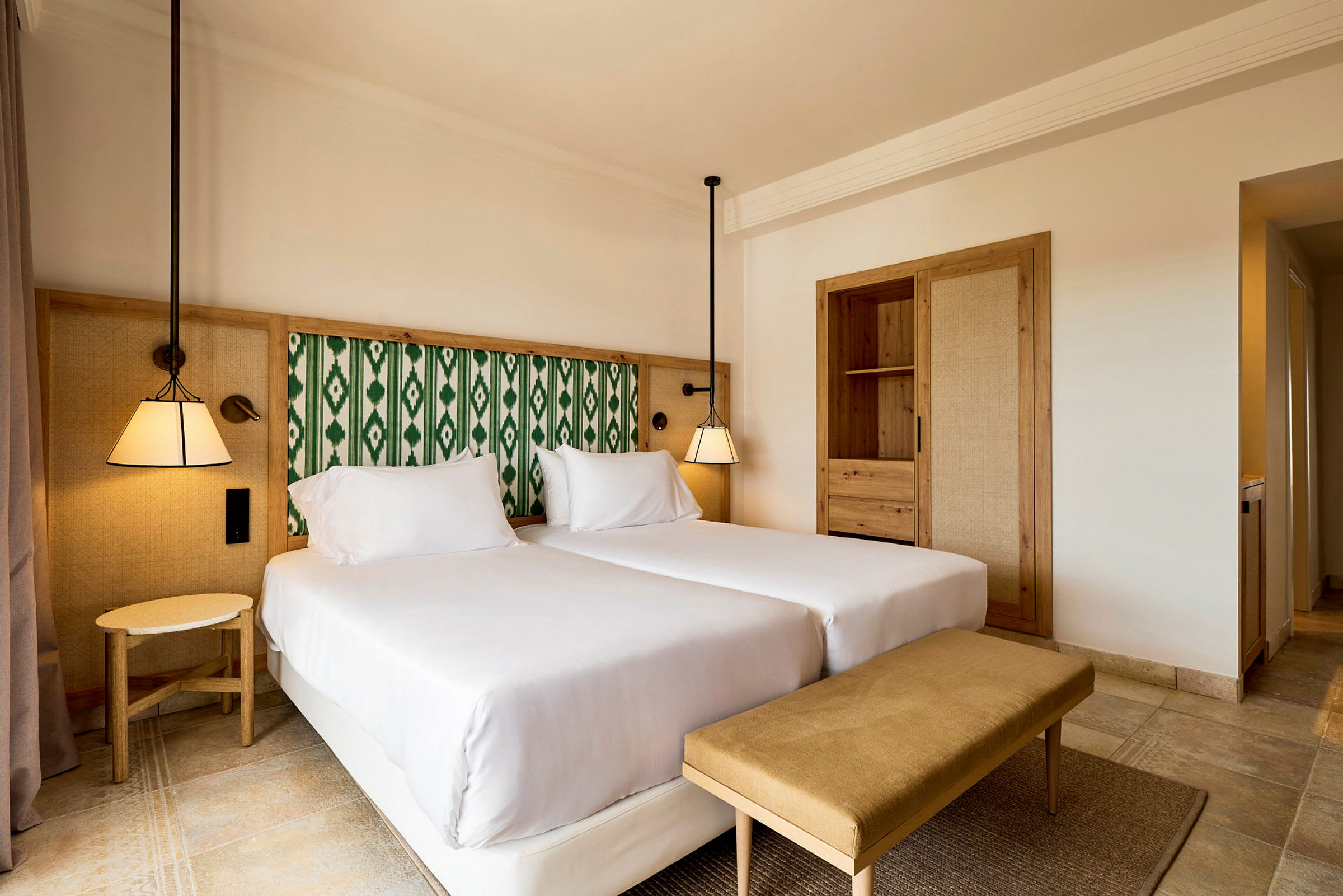 En hotellrum med två enkelsängar, en bänk och inbyggd garderob. (AI-genererad text)