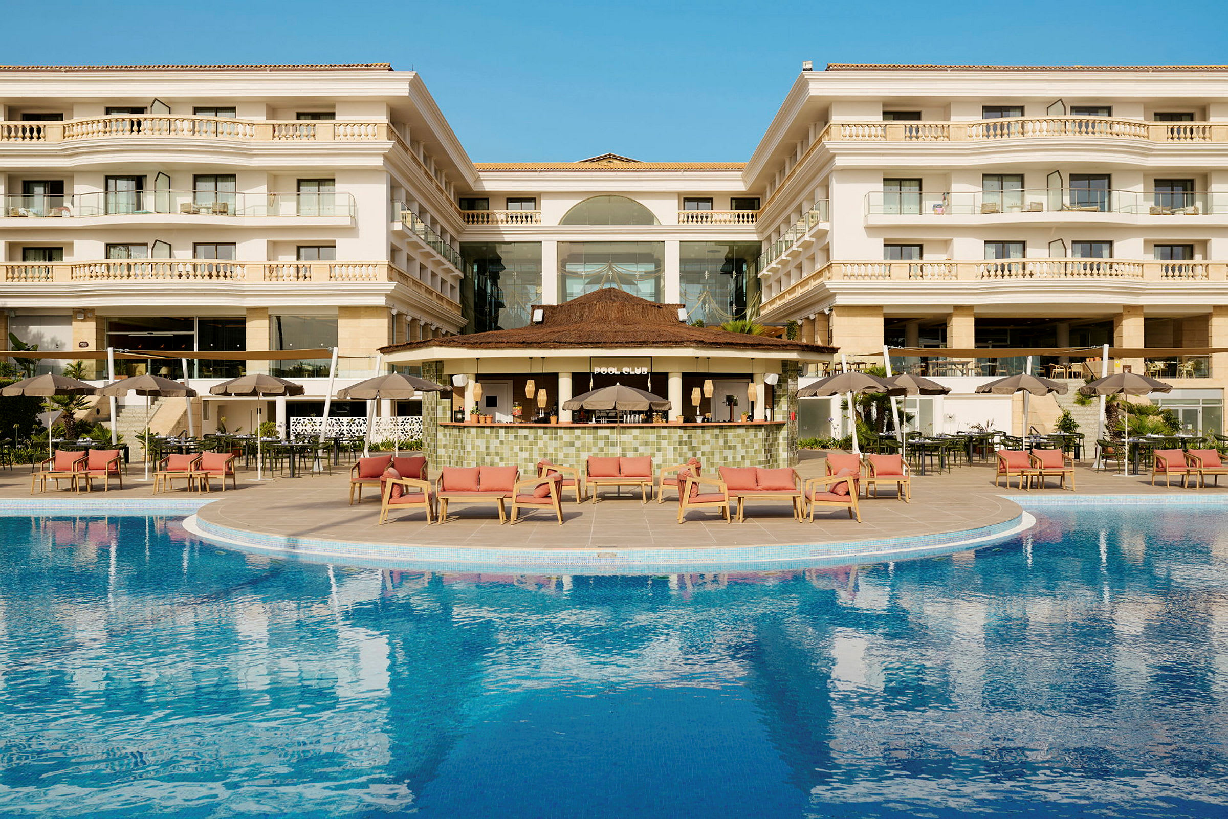 Hotellbyggnad med en pool och områden för avkoppling utanför. (AI-genererad text)