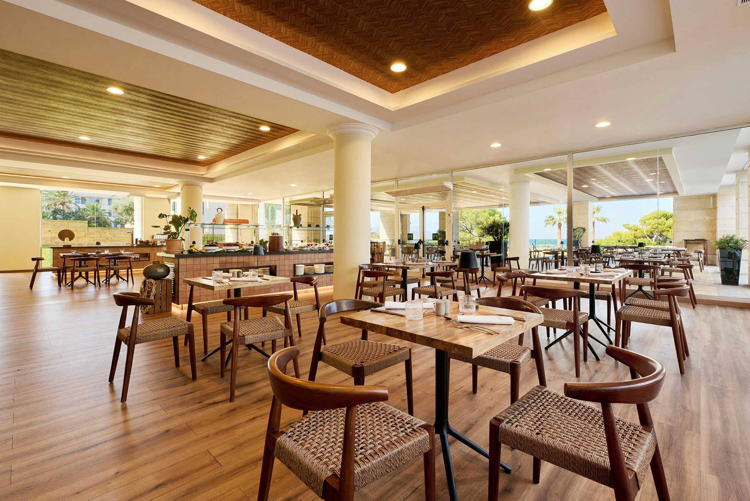 En ljus restaurang med träbord och stolar, stora fönster och en öppen planlösning. (AI-genererad text)