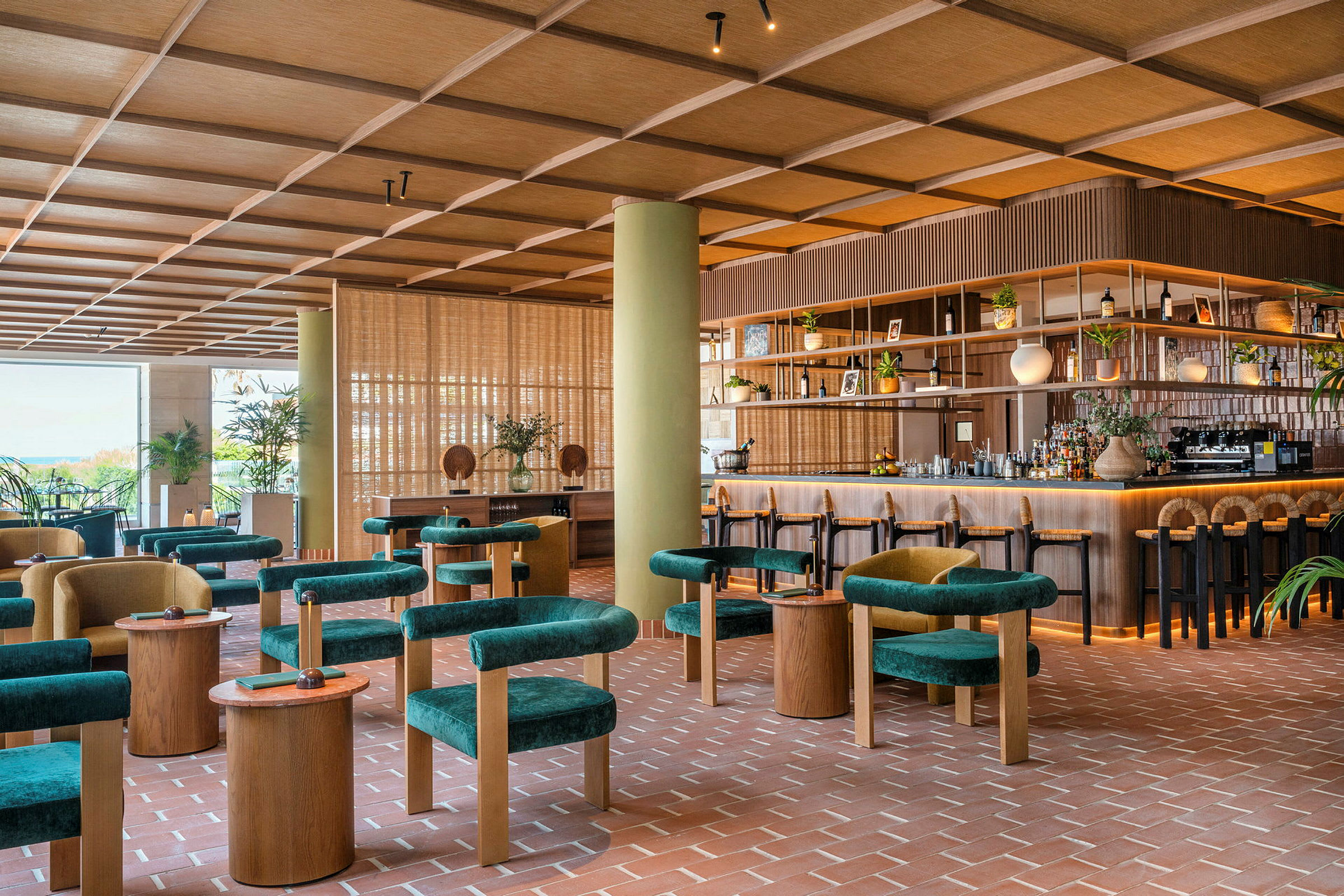 Bild av en modern bar eller restaurang med gröna sittmöbler, träbord och en välorganiserad bardisk. Interiören har en varm och inbjudande känsla. (AI-genererad text)