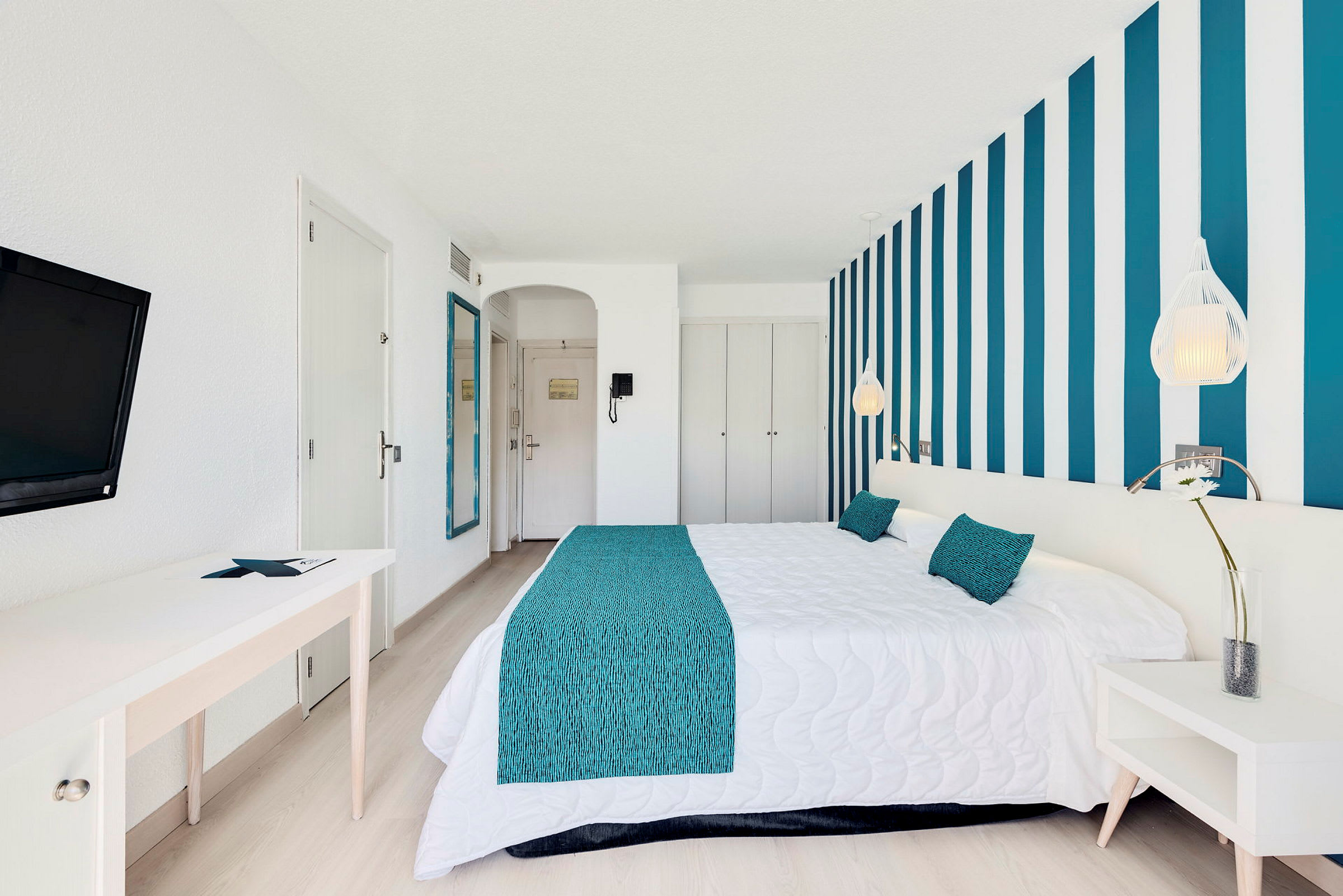 Ett hotellrum med blå och vita dekorativa detaljer och en bekväm dubbelsäng. (AI-genererad text)