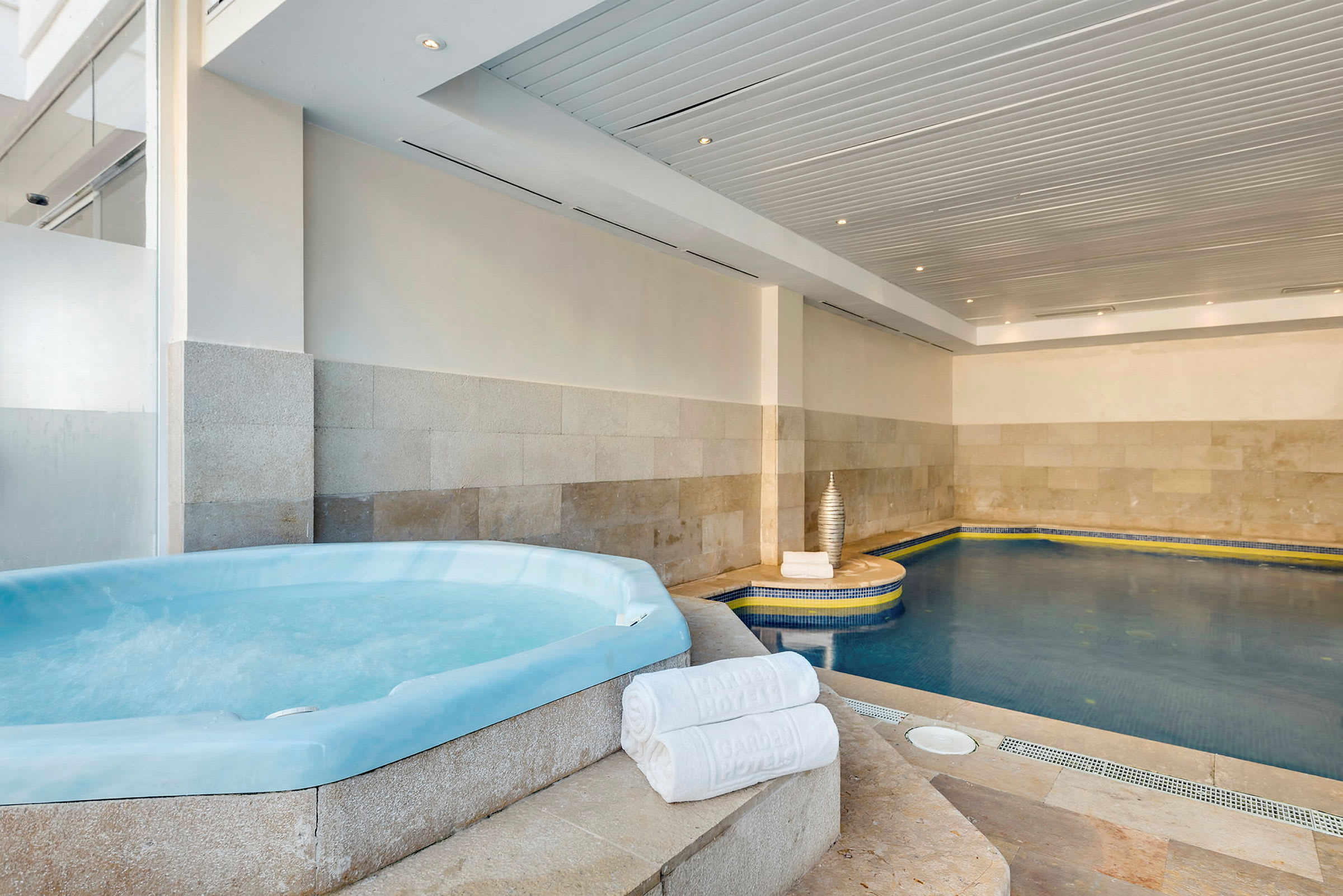 Bild av en inomhuspool med en jacuzzi och handdukar placerade på kanten. (AI-genererad text)