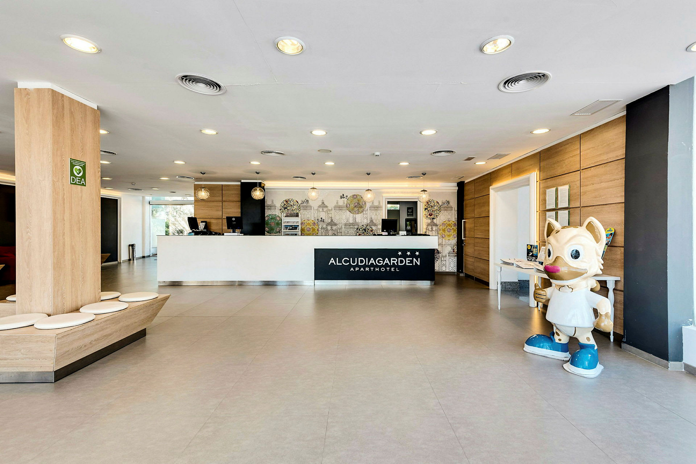 Receptionen på Alcudia Garden med en stor kattliknande staty till höger. (AI-genererad text)