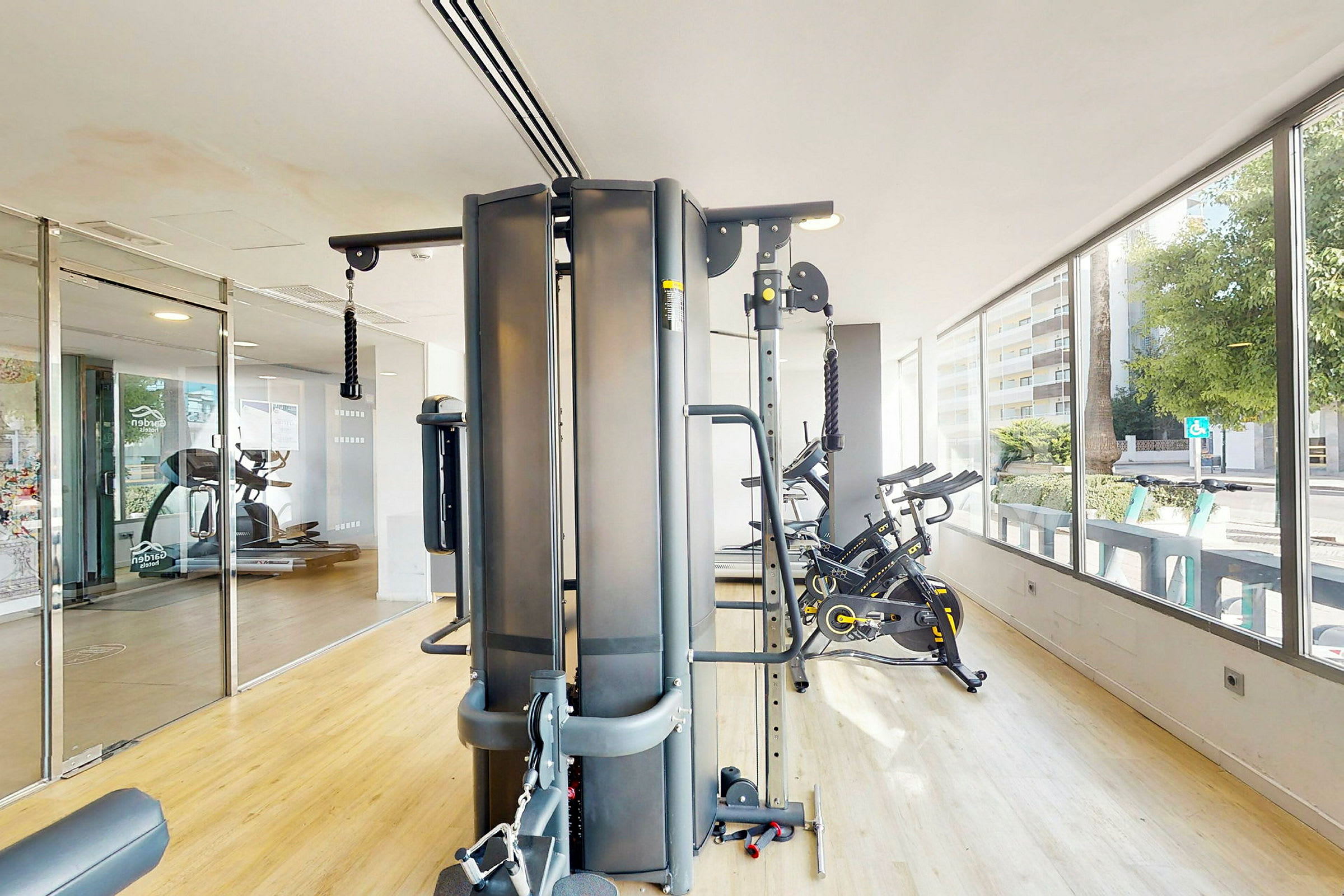 Ett gym med olika träningsmaskiner inklusive motionscyklar och en multigymmaskin. (AI-genererad text)