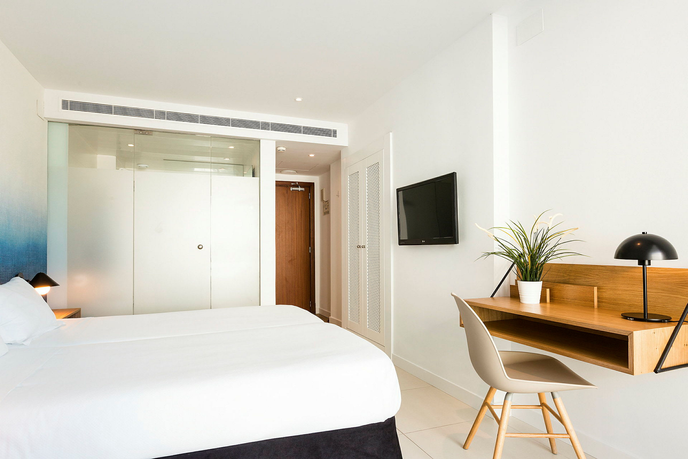 Ett hotellrum med en stor säng, ett skrivbord och en tv monterad på väggen. (AI-genererad text)