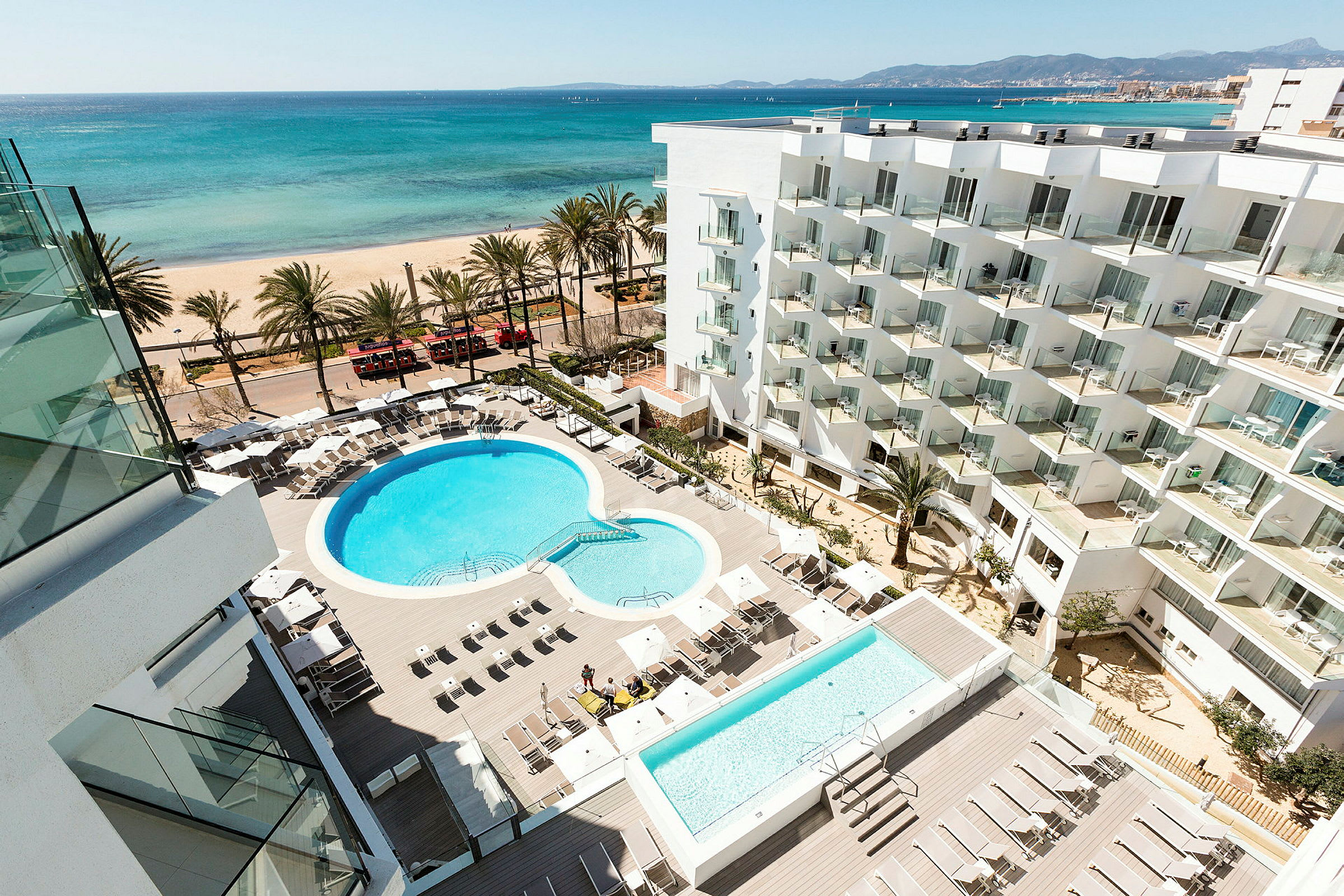 Hotellområde med pool och solstolar, strand och hav i bakgrunden. (AI-genererad text)