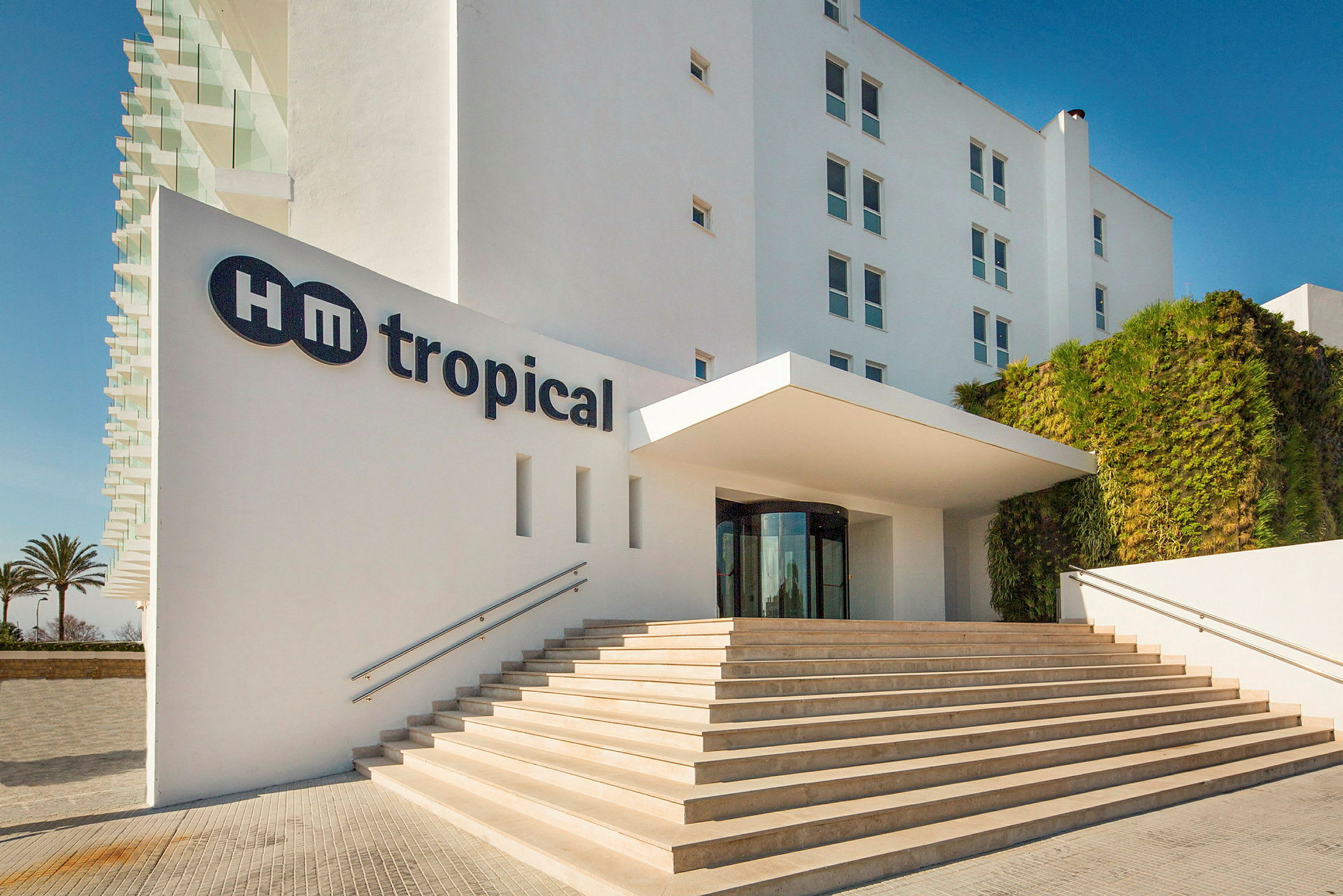 Bild föreställer ingången till HM Tropical hotell med steg som leder upp till entrén. (AI-genererad text)