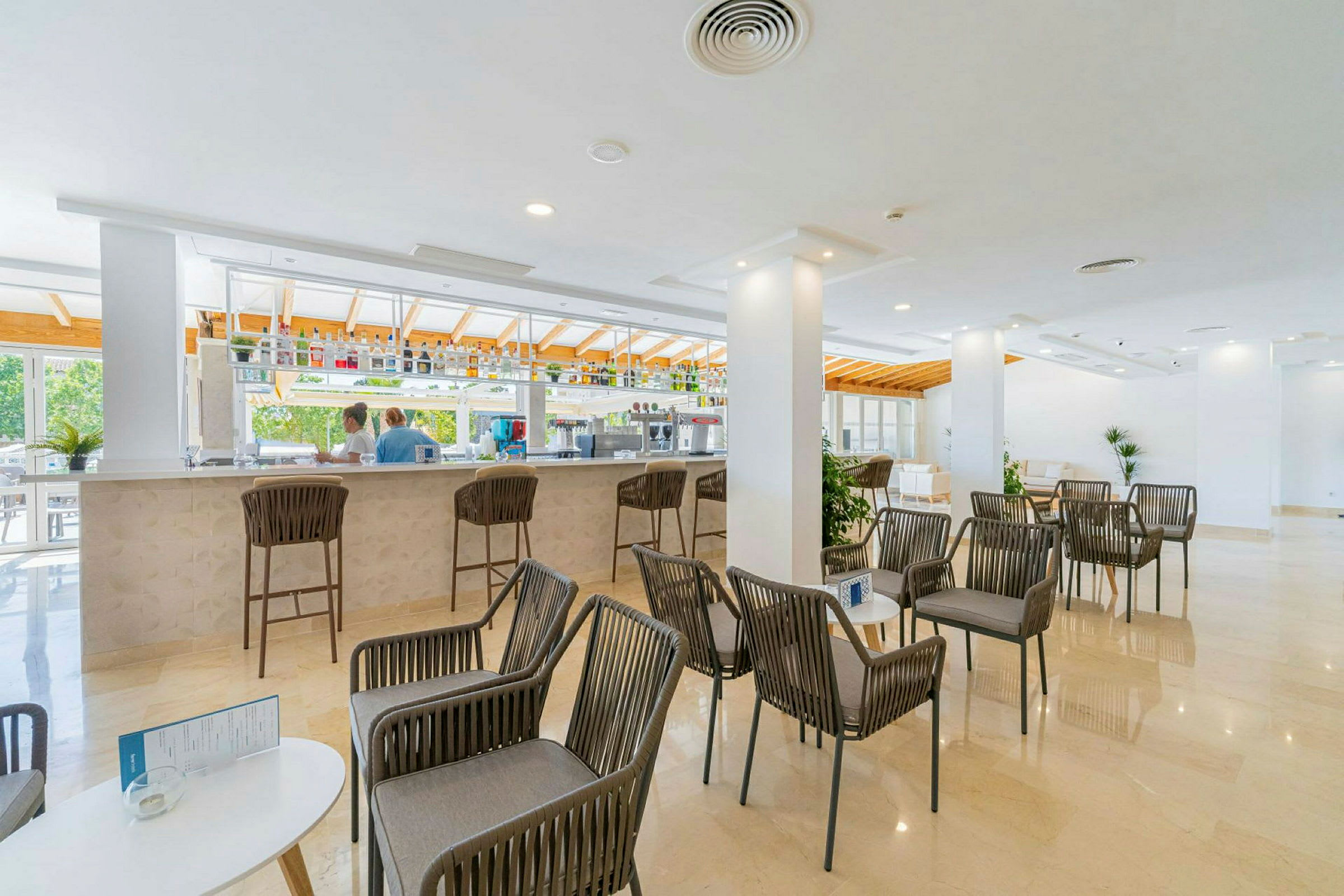 En ljus och modern bar med sittmöbler och bord i förgrunden. (AI-genererad text)