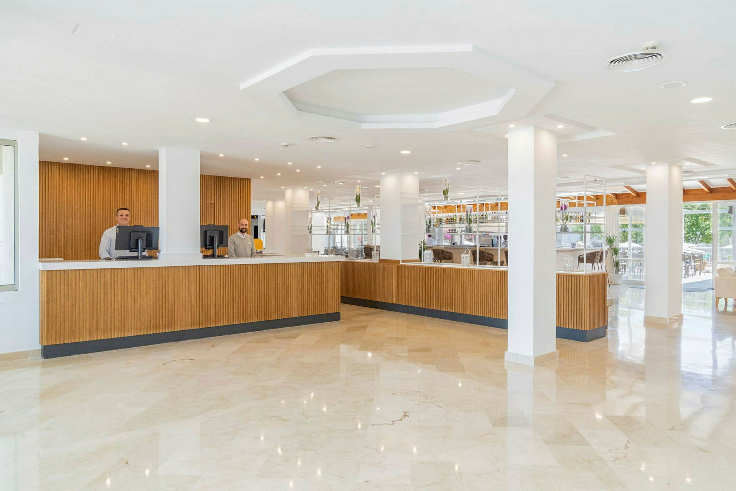 Receptionen och lobbyområdet på ett hotell med en lång disk i trä och ljusa inredningsdetaljer. (AI-genererad text)