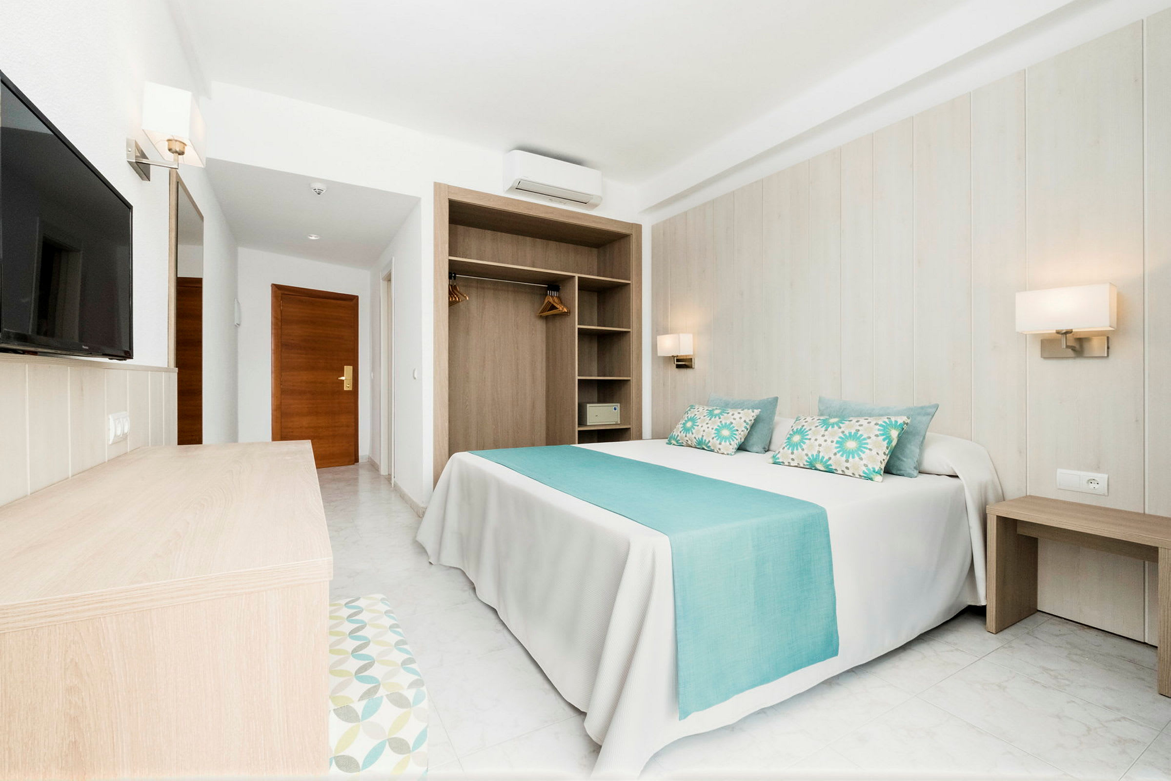 Hotelrum med en dubbelsäng, blå detaljer och en garderob. (AI-genererad text)