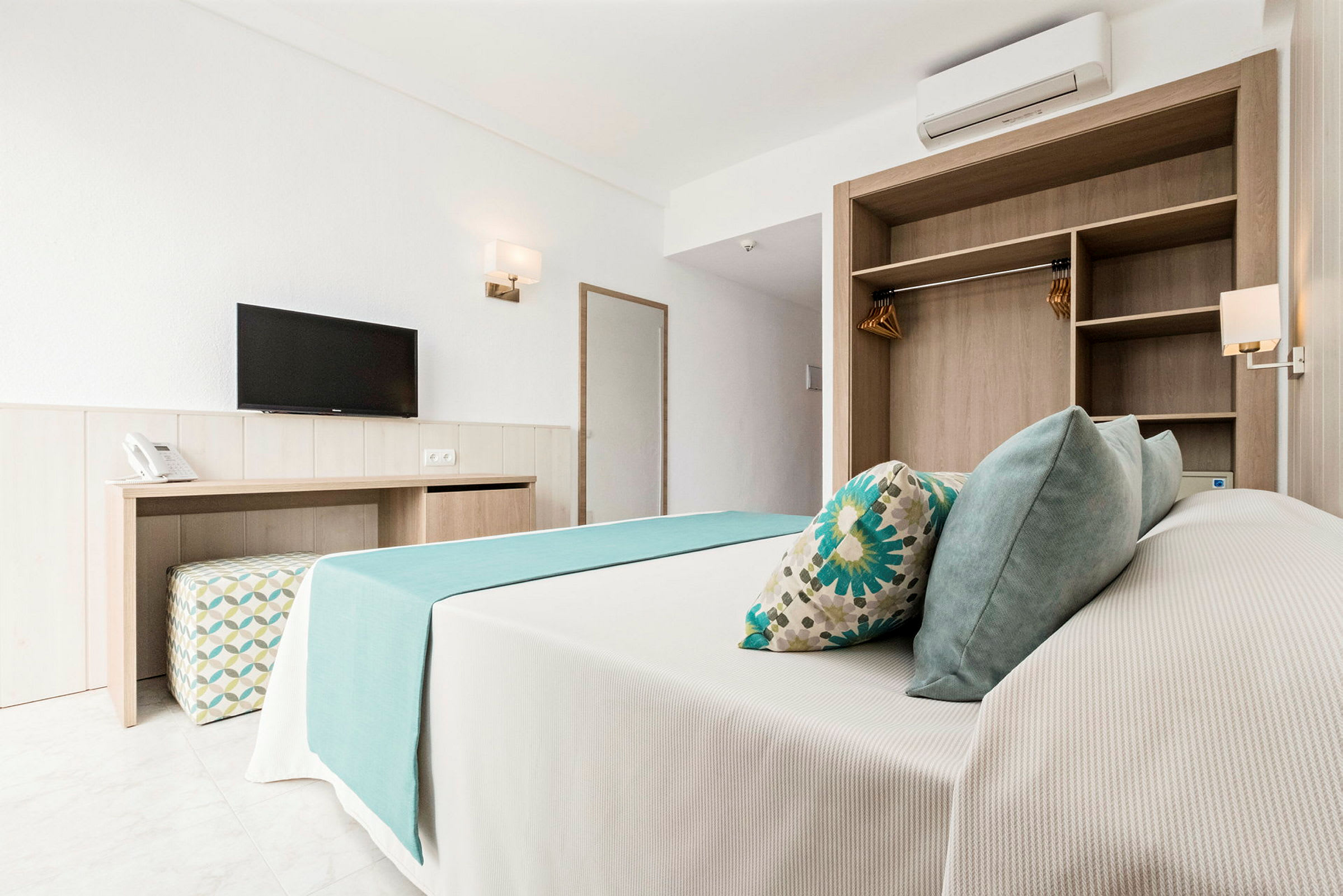 Ett hotellrum med en säng, TV, garderob och skrivbord. (AI-genererad text)