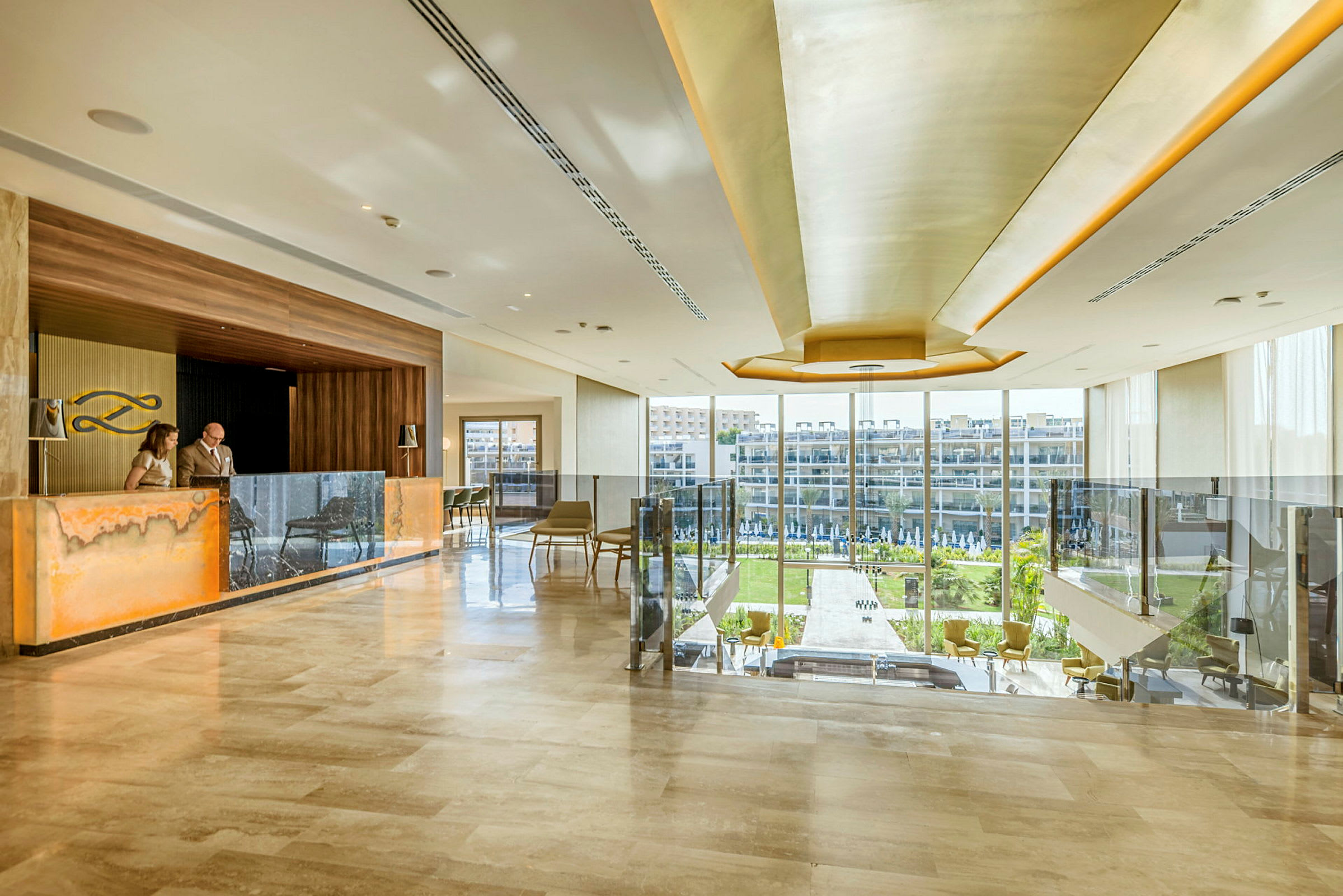 Elegant hotellobby med reception och stora glasfönster som vetter mot en grönskande utsikt. (AI-genererad text)