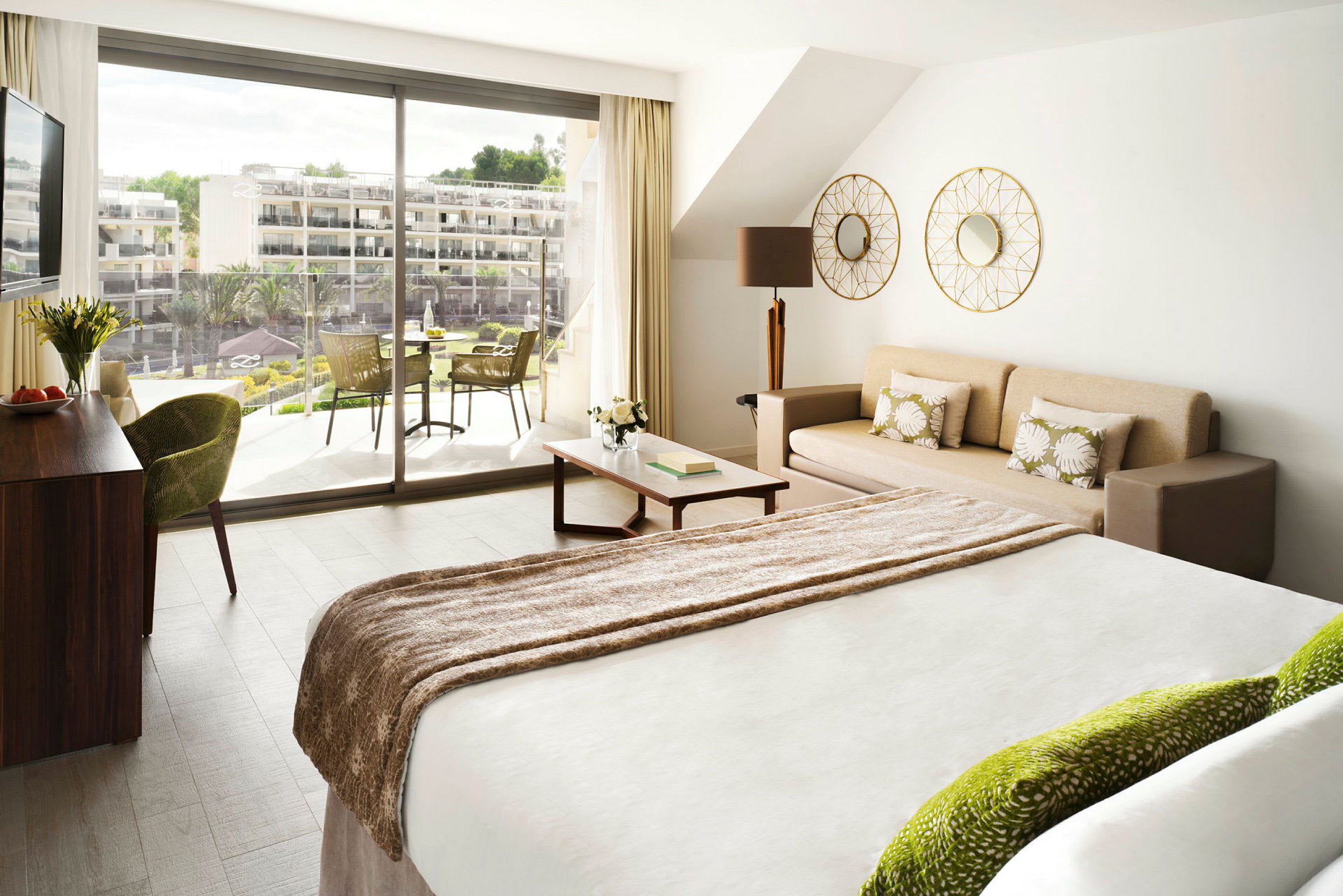 Ett ljust hotellrum med en säng, en soffa, och en balkong utanför. (AI-genererad text)