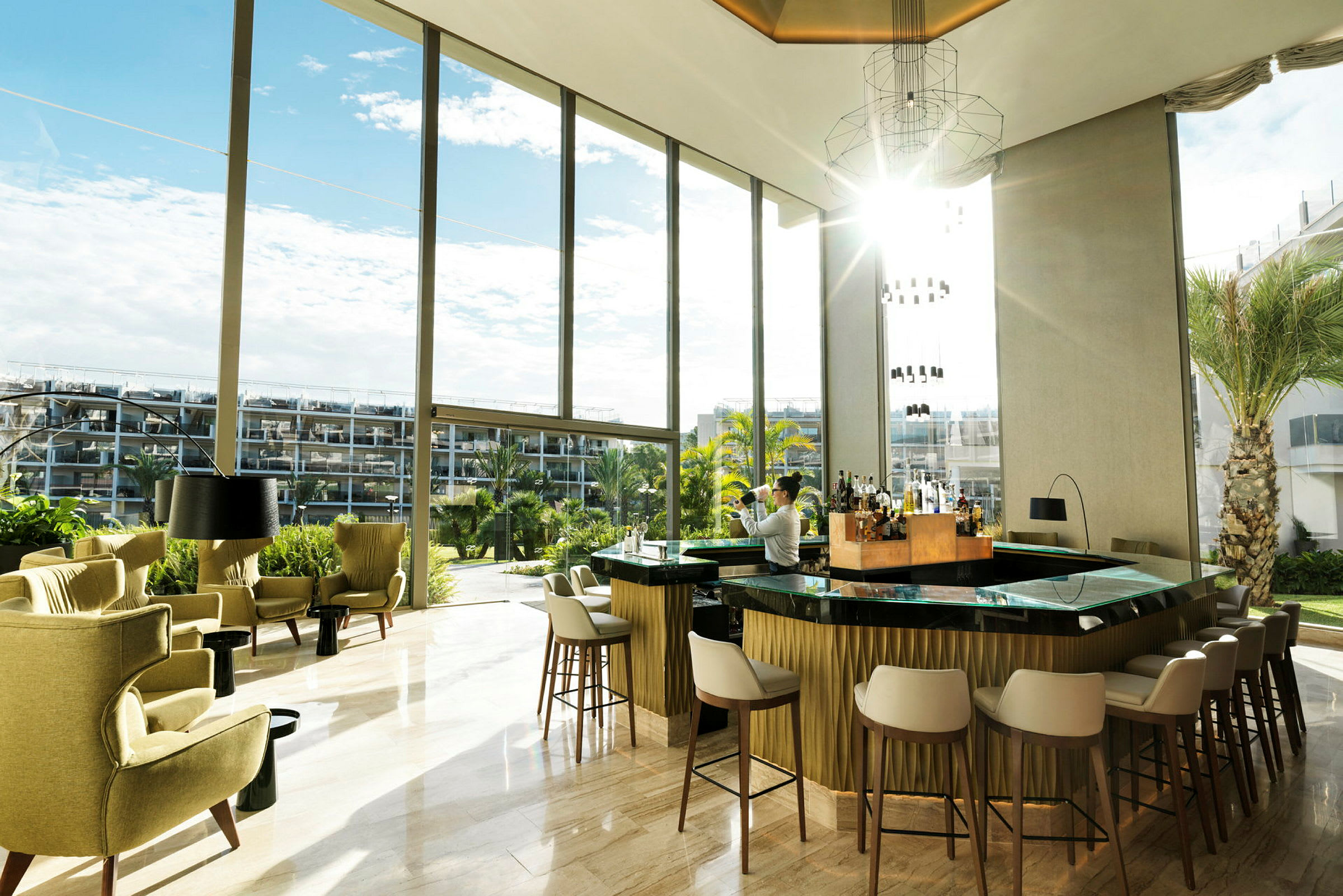 En eleganta hotellbar med stora fönster och utsikt över en trädgård. (AI-genererad text)