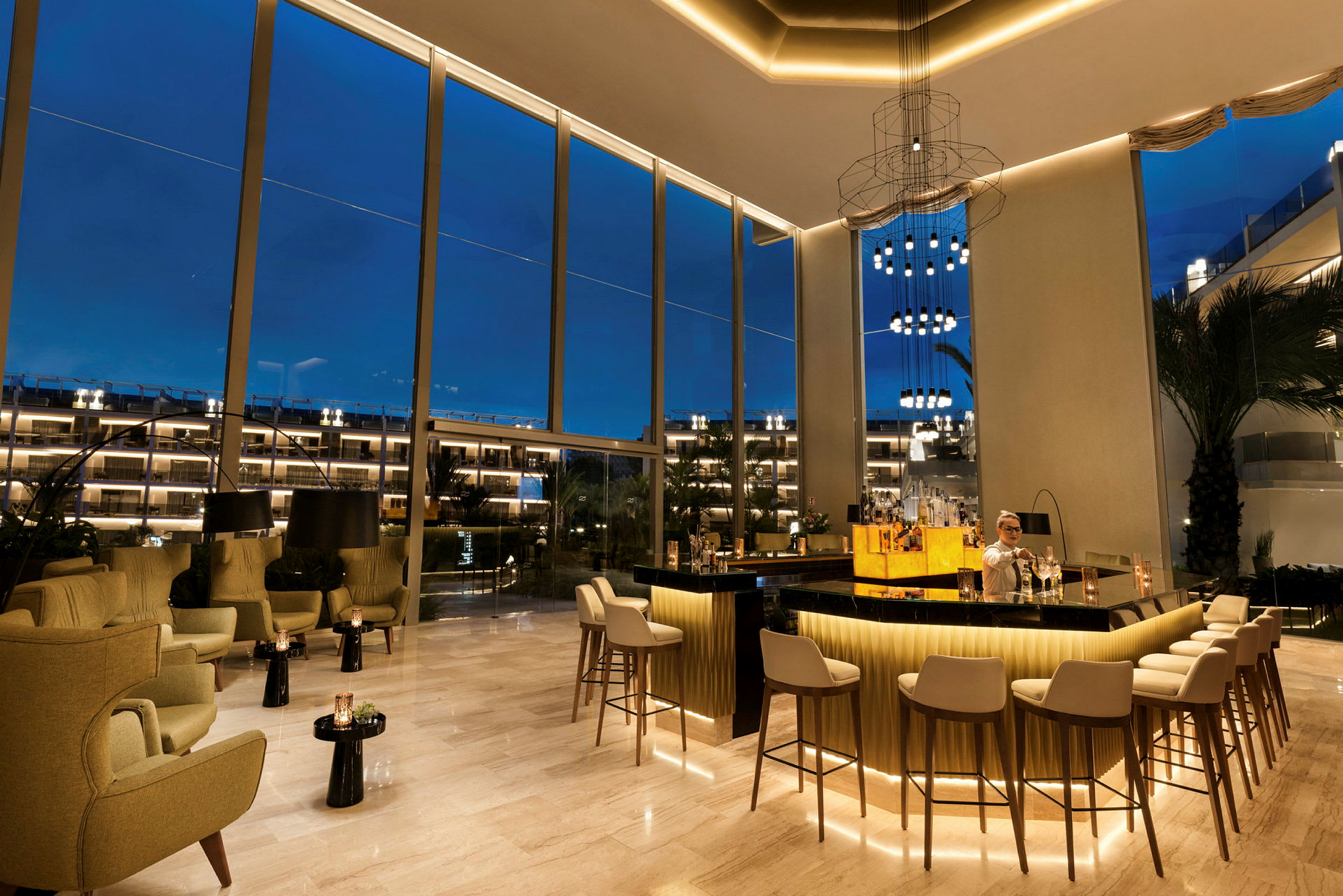 En elegant bar med sittplatser och höga fönster som vetter mot kvällsbelysningen utomhus. (AI-genererad text)