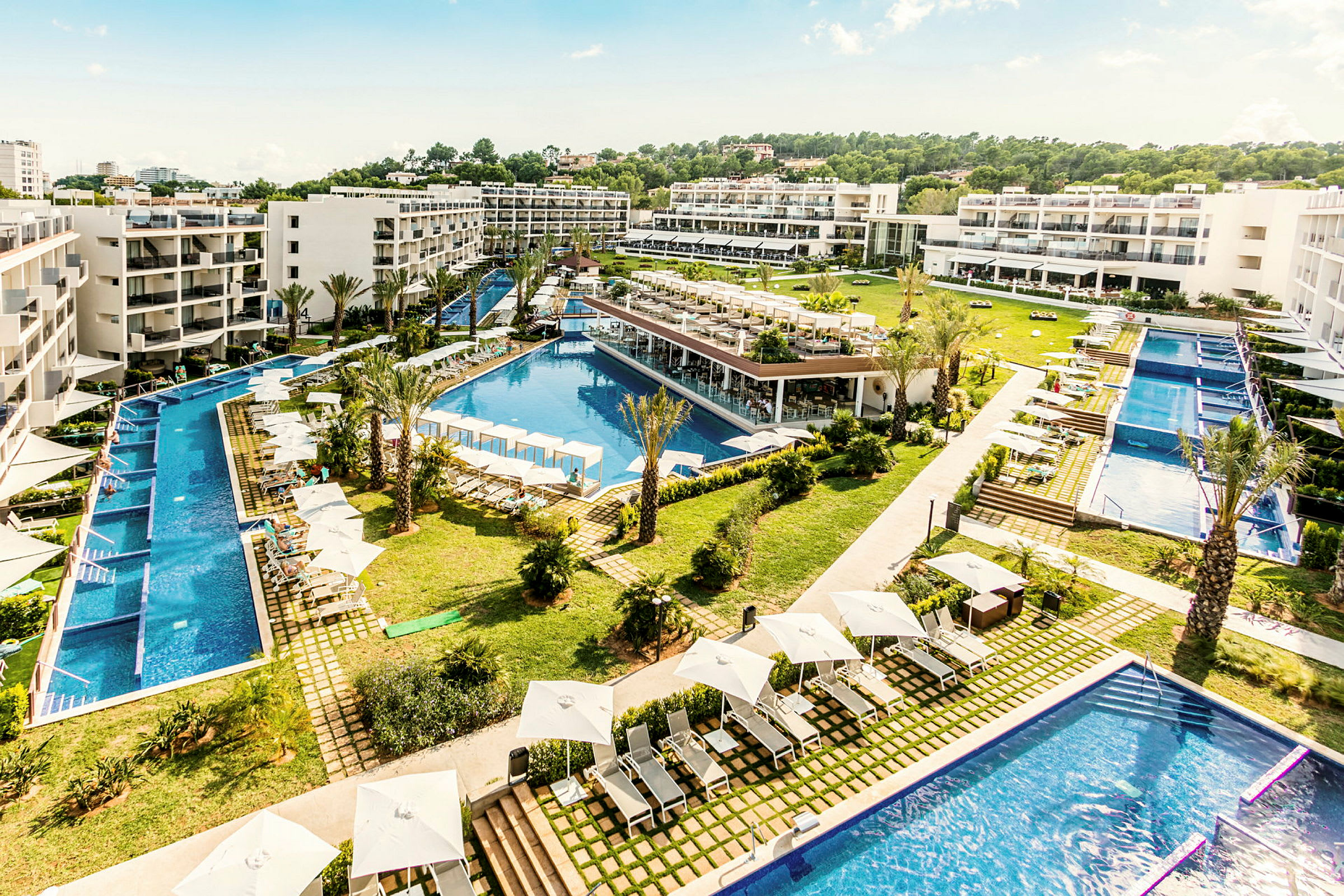 Hotellkomplex med pooler, solstolar och grönområde. (AI-genererad text)