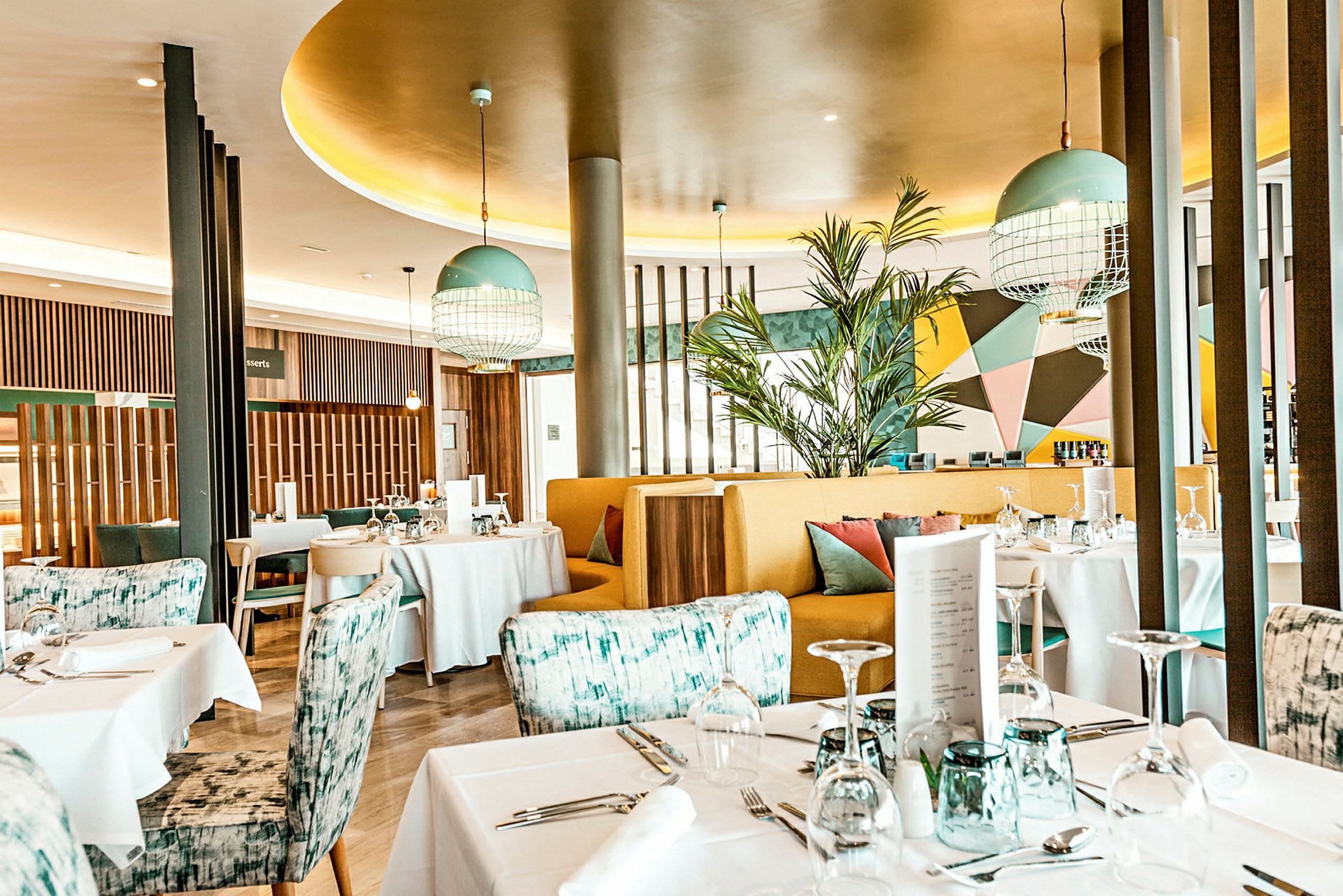 En modern och färgglad restaurang med dukade bord och stilfull inredning. (AI-genererad text)