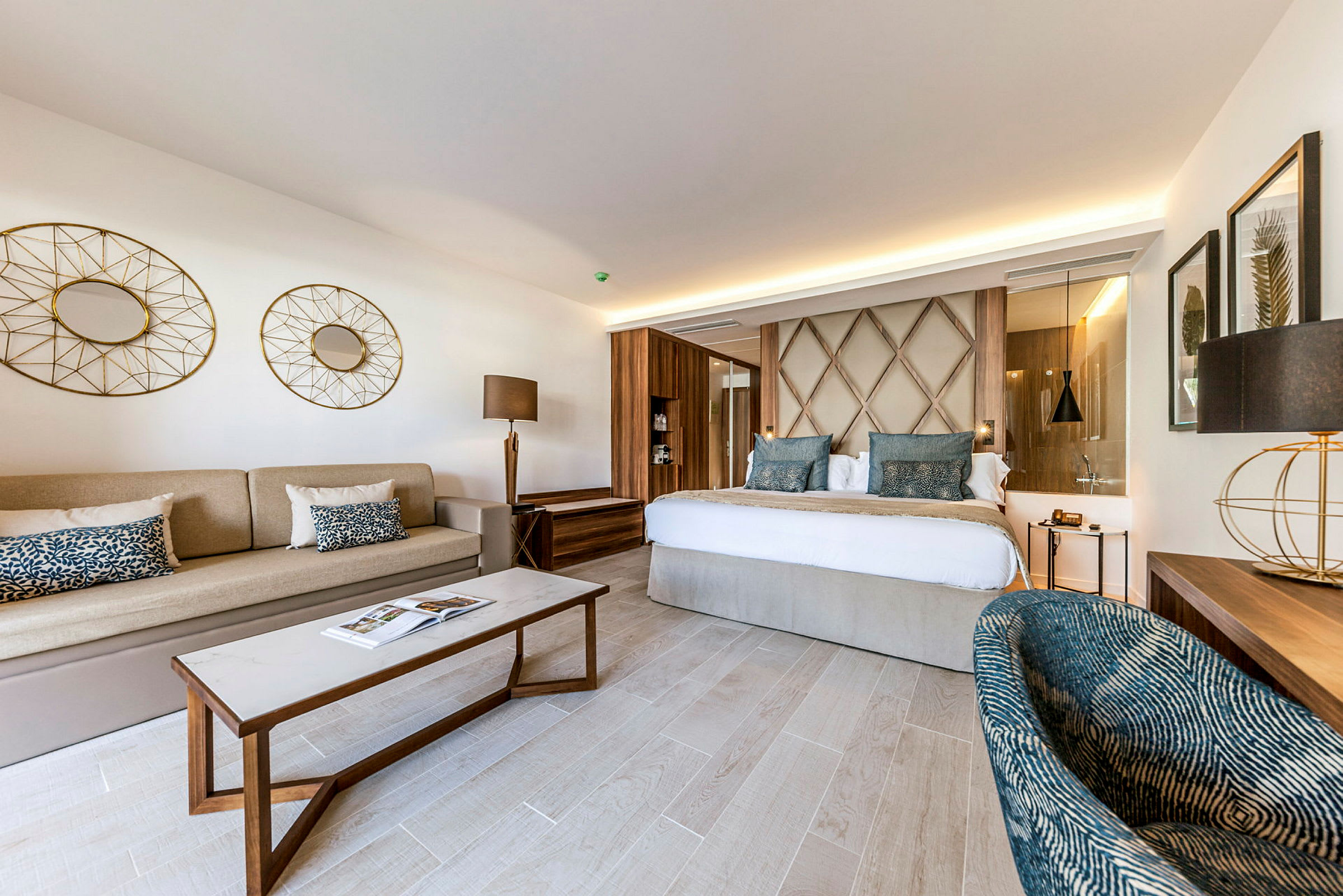 Ett elegant hotellrum med en dubbelsäng, en soffa, ett soffbord och moderna inredningsdetaljer. (AI-genererad text)
