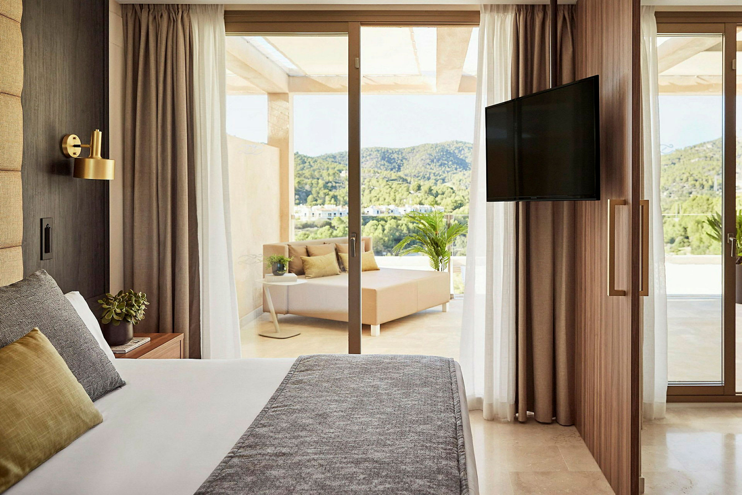 Ett hotellrum med säng, sittområde utomhus och en TV. (AI-genererad text)