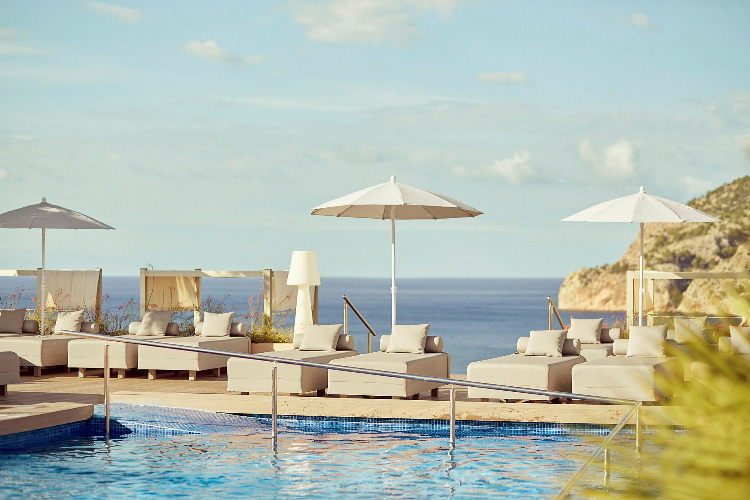 Poolområde med solstolar och parasoll med utsikt över havet. (AI-genererad text)