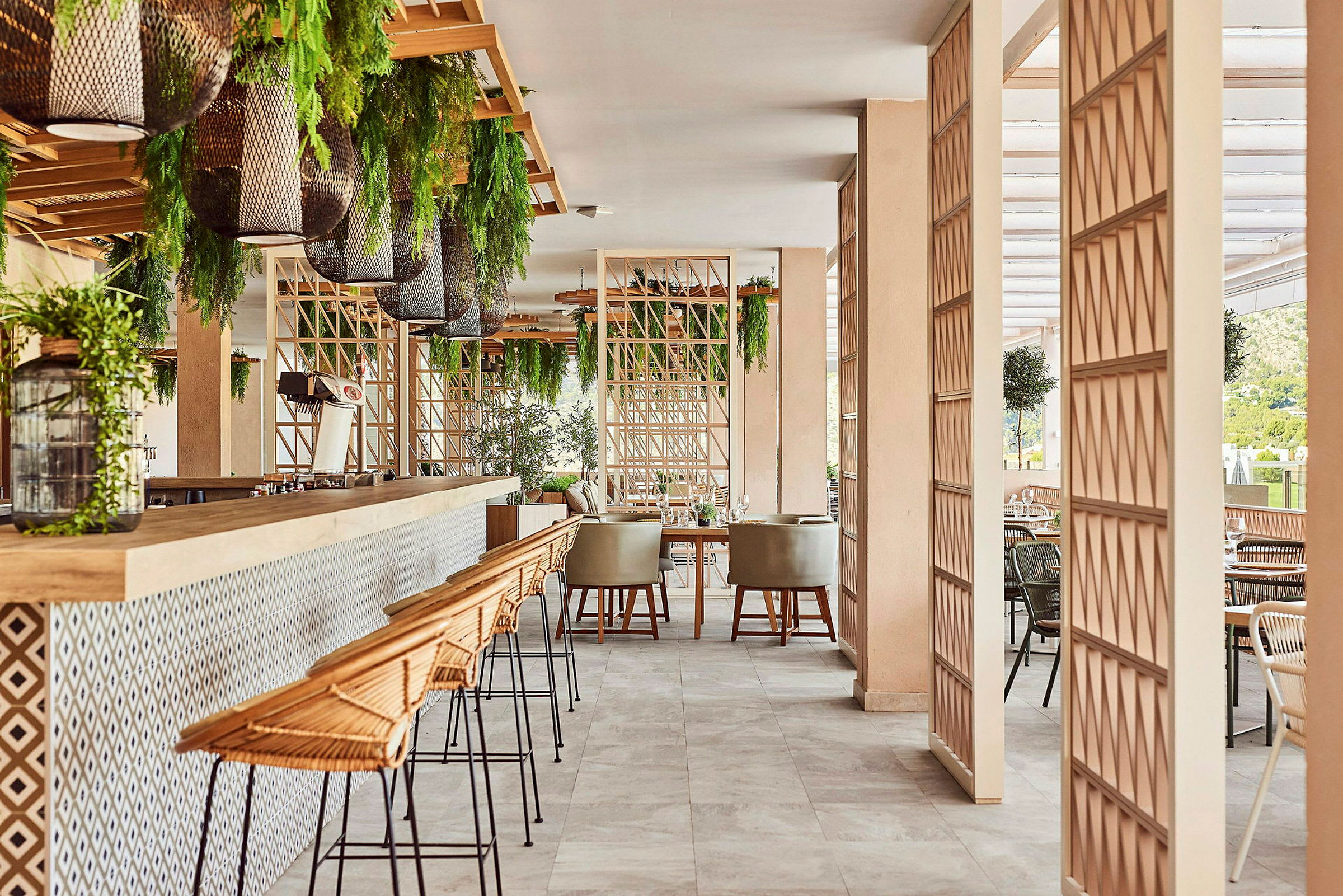 En modern restaurangmiljö med barstolar, bord och gröna växter. (AI-genererad text)