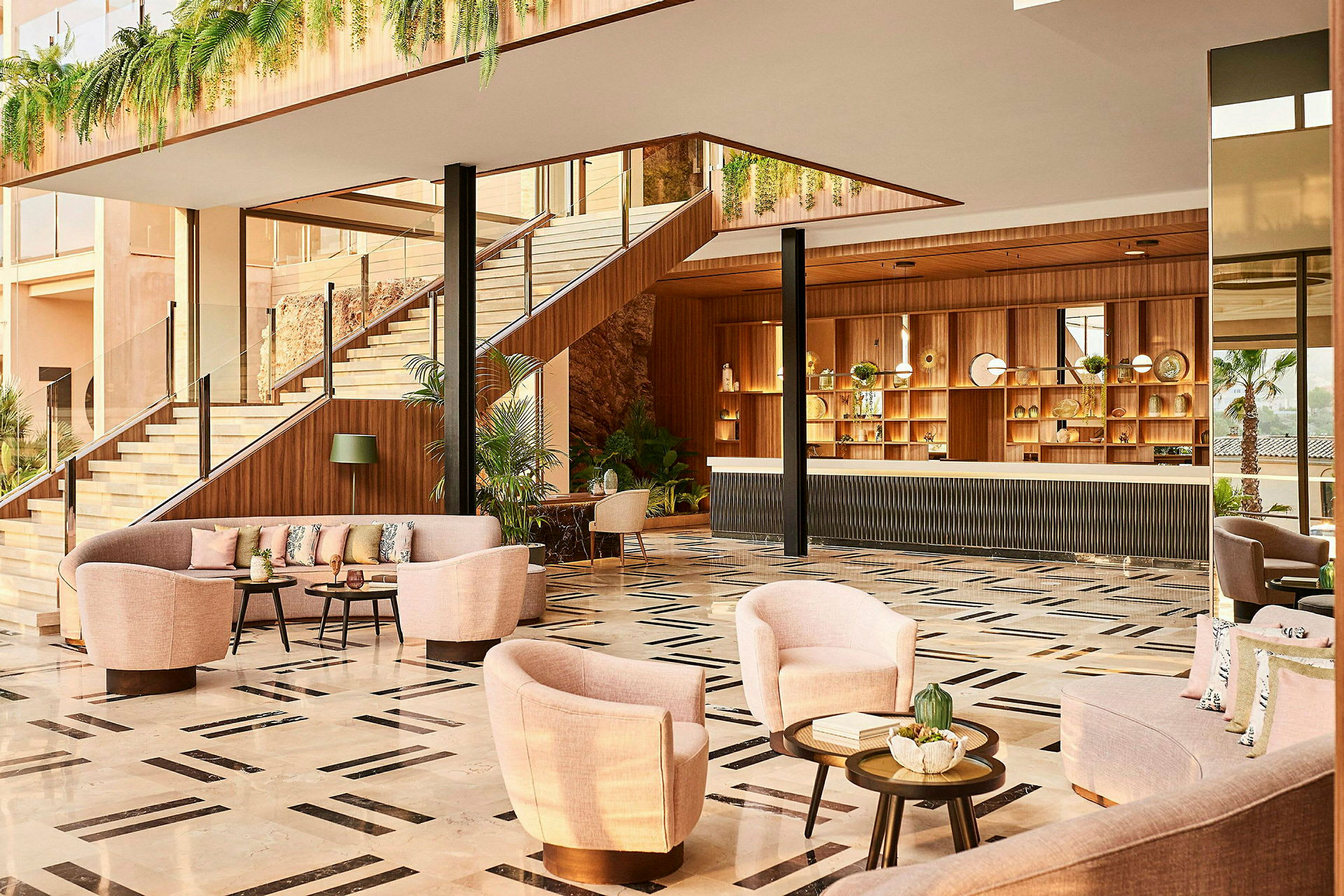 Ett hotellobby med soffor och fåtöljer, en receptionsdisk och trappa omgiven av växtinredning. (AI-genererad text)