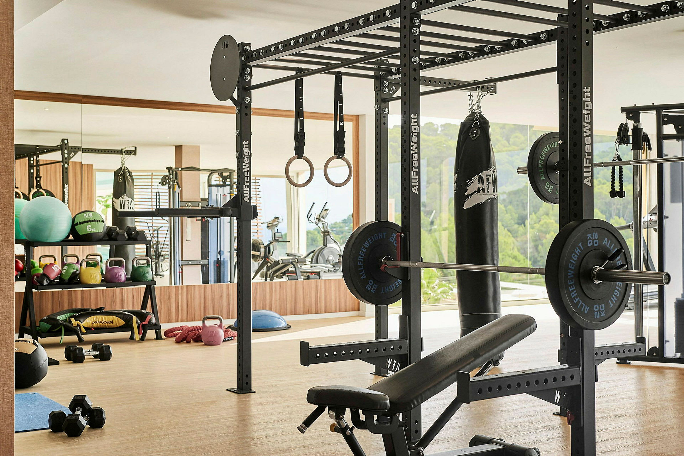 Ett gym med träningsutrustning, inklusive vikter, kettlebells, ringar och en boxningssäck. (AI-genererad text)