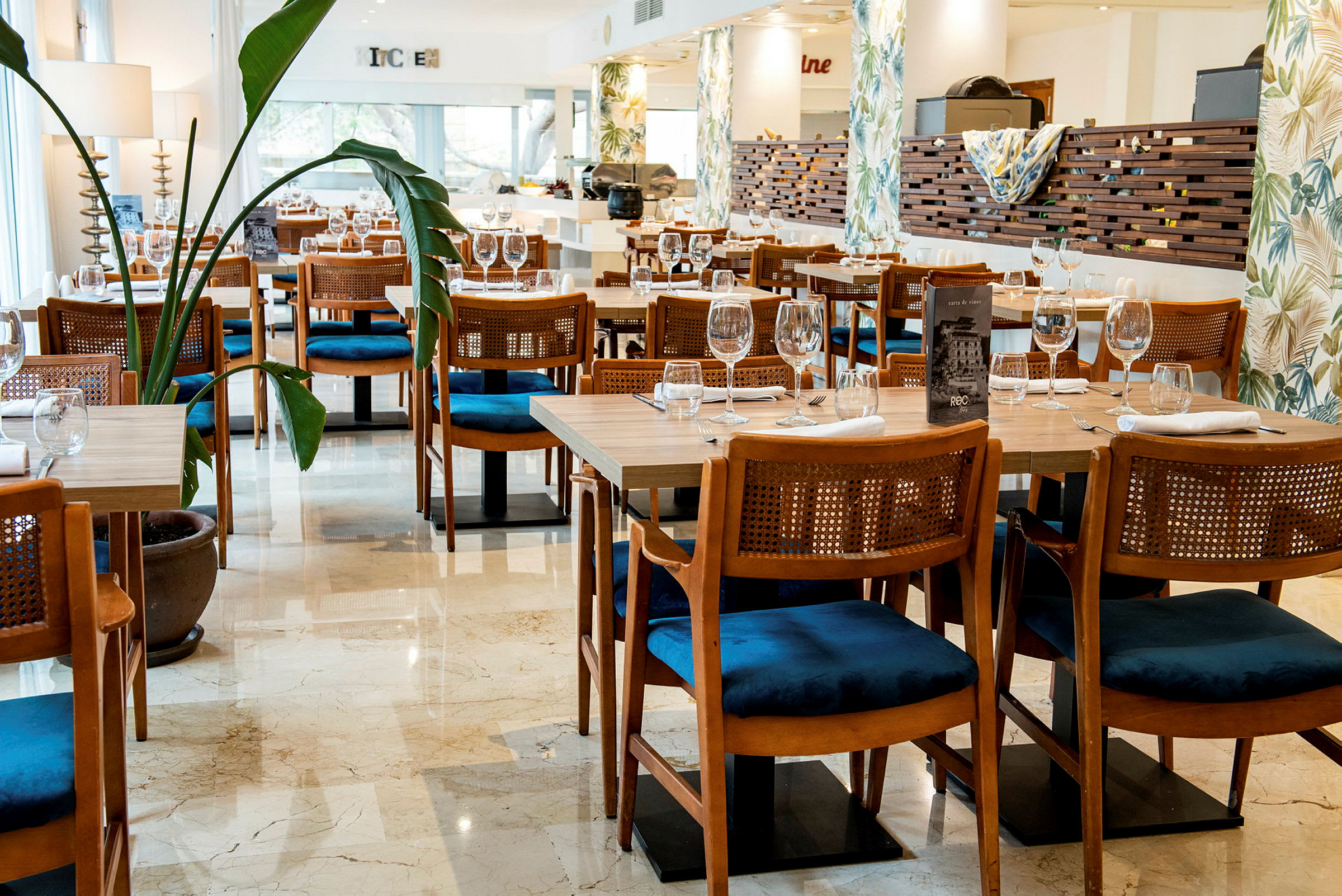 En restaurang med dukade bord och stolar samt växter i krukor. (AI-genererad text)