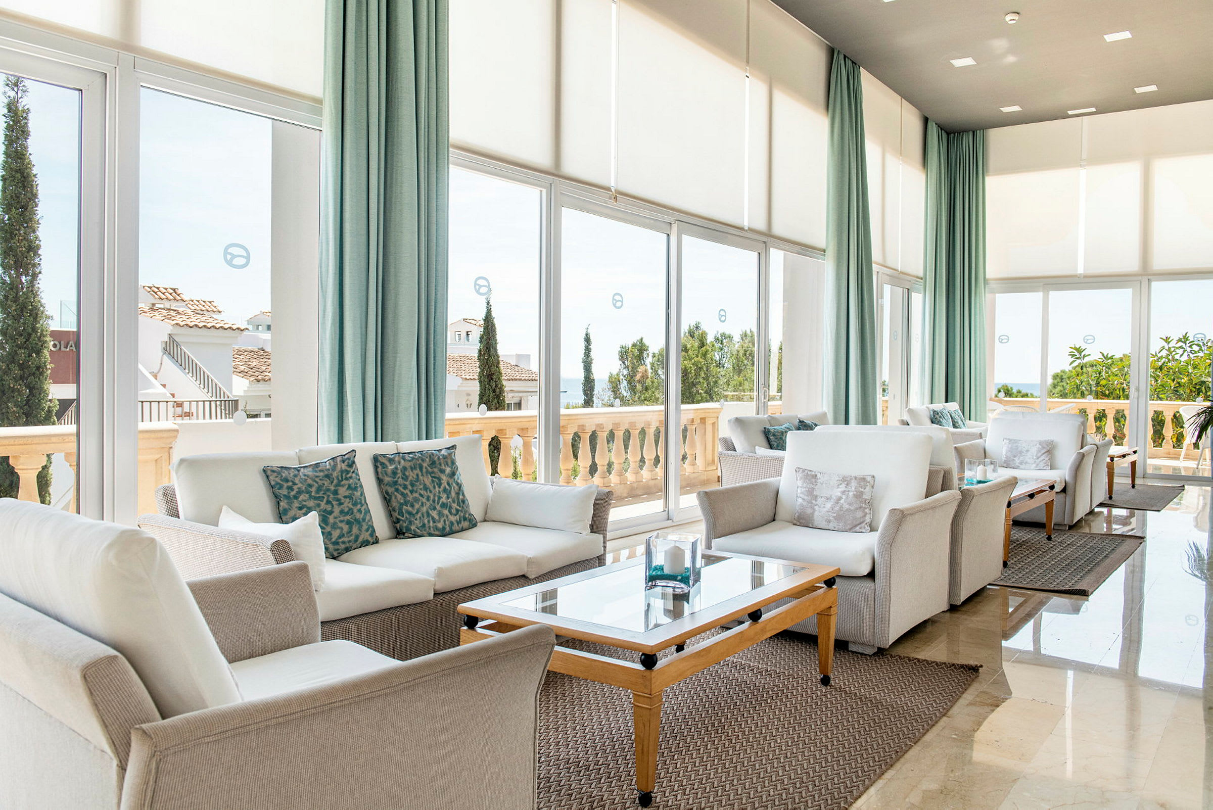 En ljus lounge med moderna soffmöbler och stora fönster som vetter mot en terrass. (AI-genererad text)