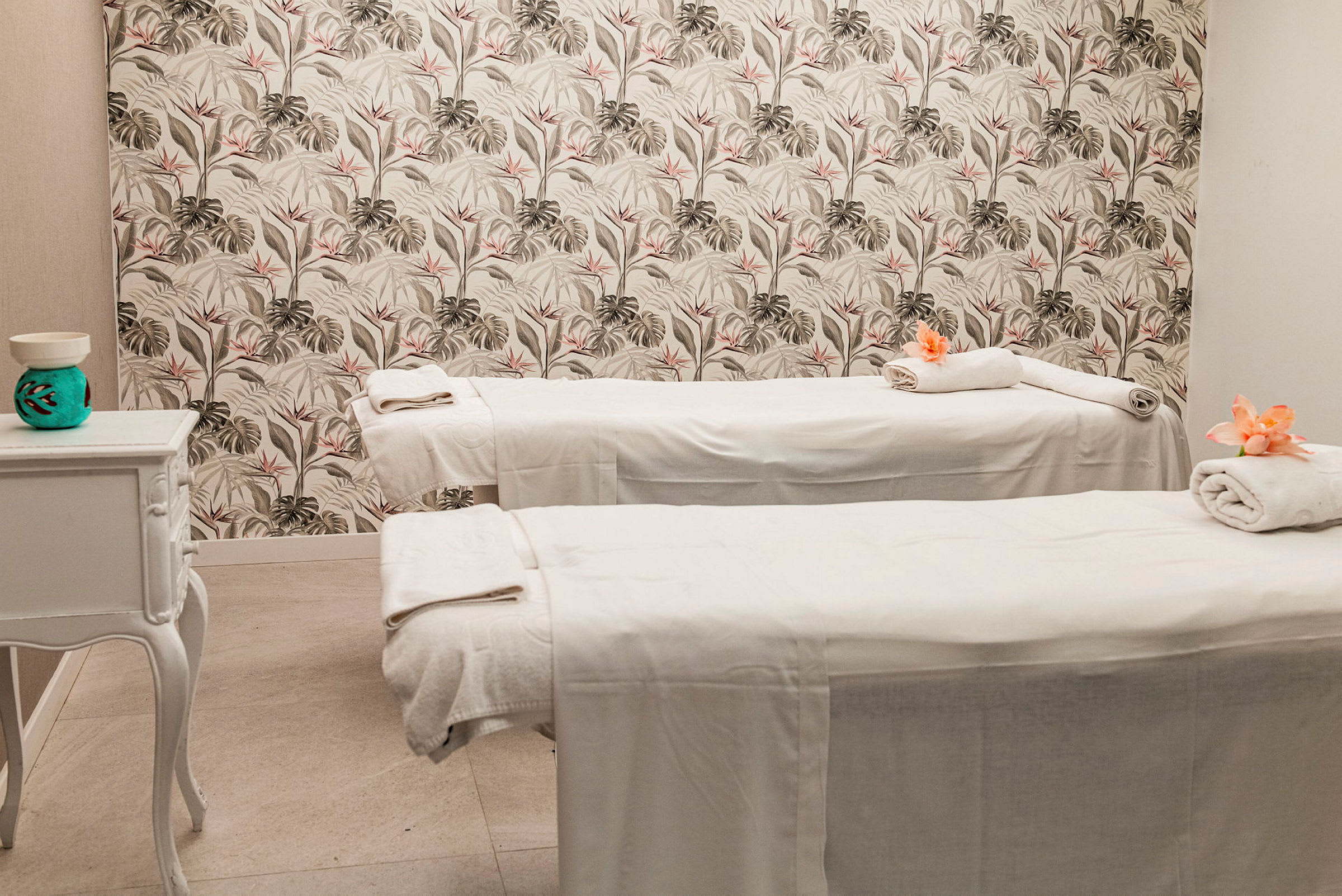 Två massagebänkar i ett rum med blommönstrad tapet. (AI-genererad text)
