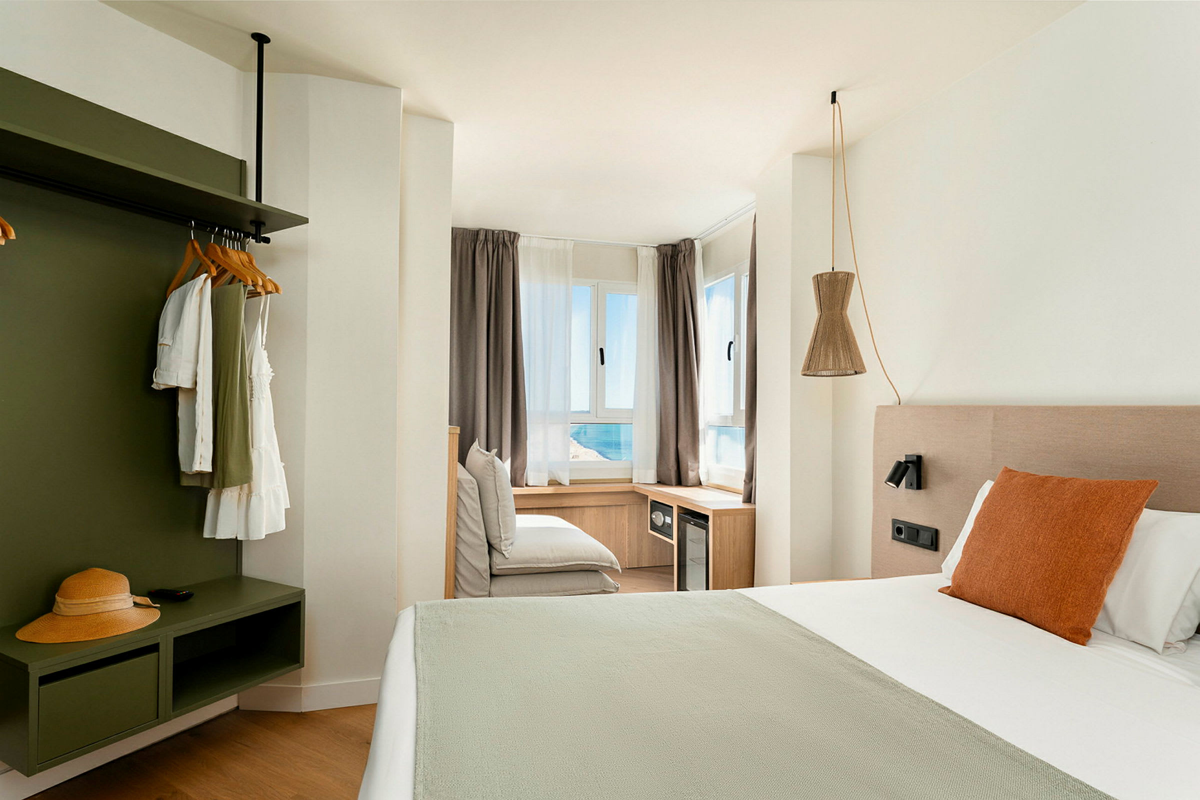 Ett ljust och modernt hotellrum med en stor säng och utsikt mot havet genom fönstren. (AI-genererad text)