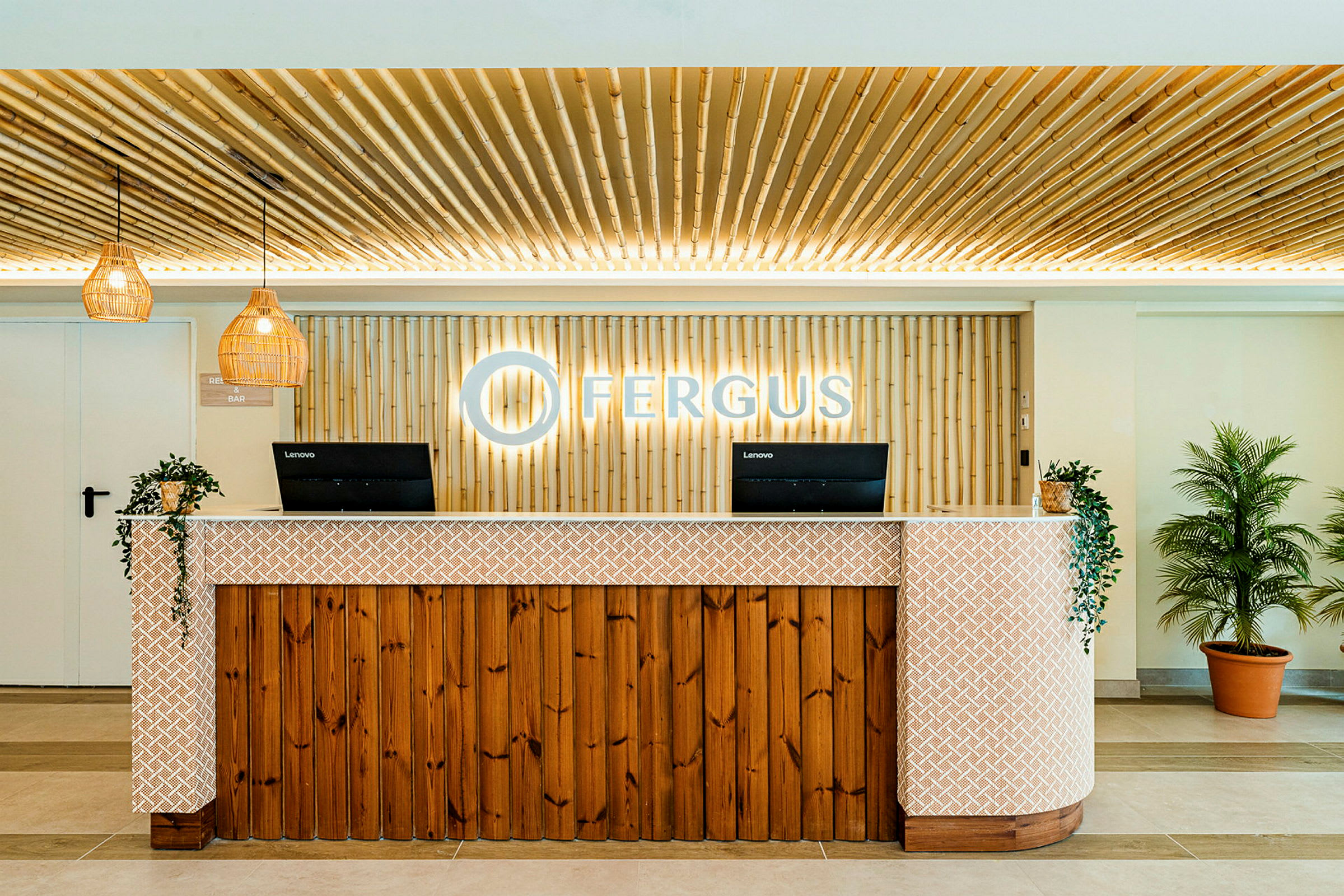 Reception med en trädisk, vägg av bambu, två datorskärmar och växter på sidorna. (AI-genererad text)