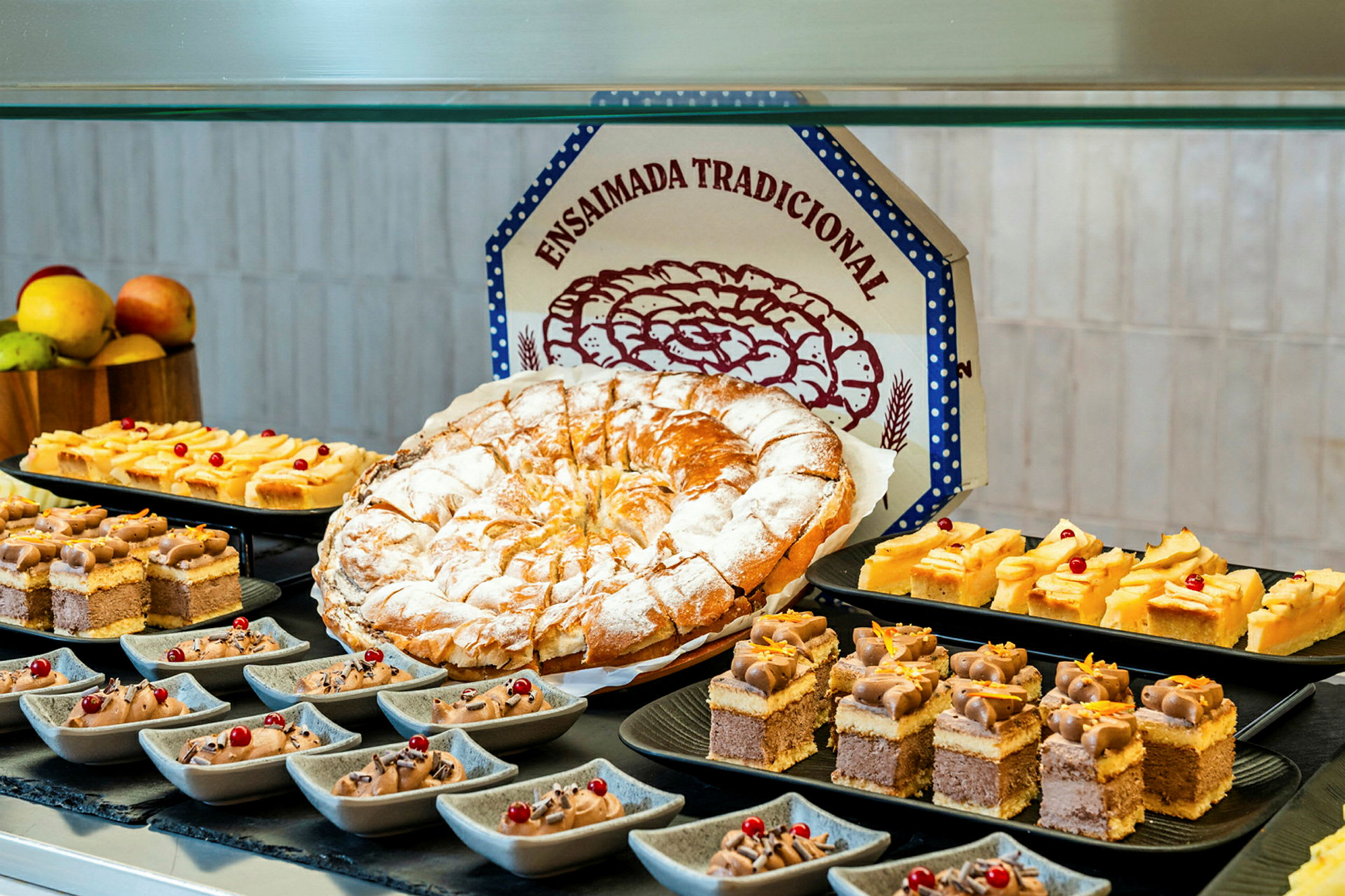 Ett bord med olika bakverk, inklusive en stor rund kaka, små tårtbitar och desserter i små skålar. (AI-genererad text)