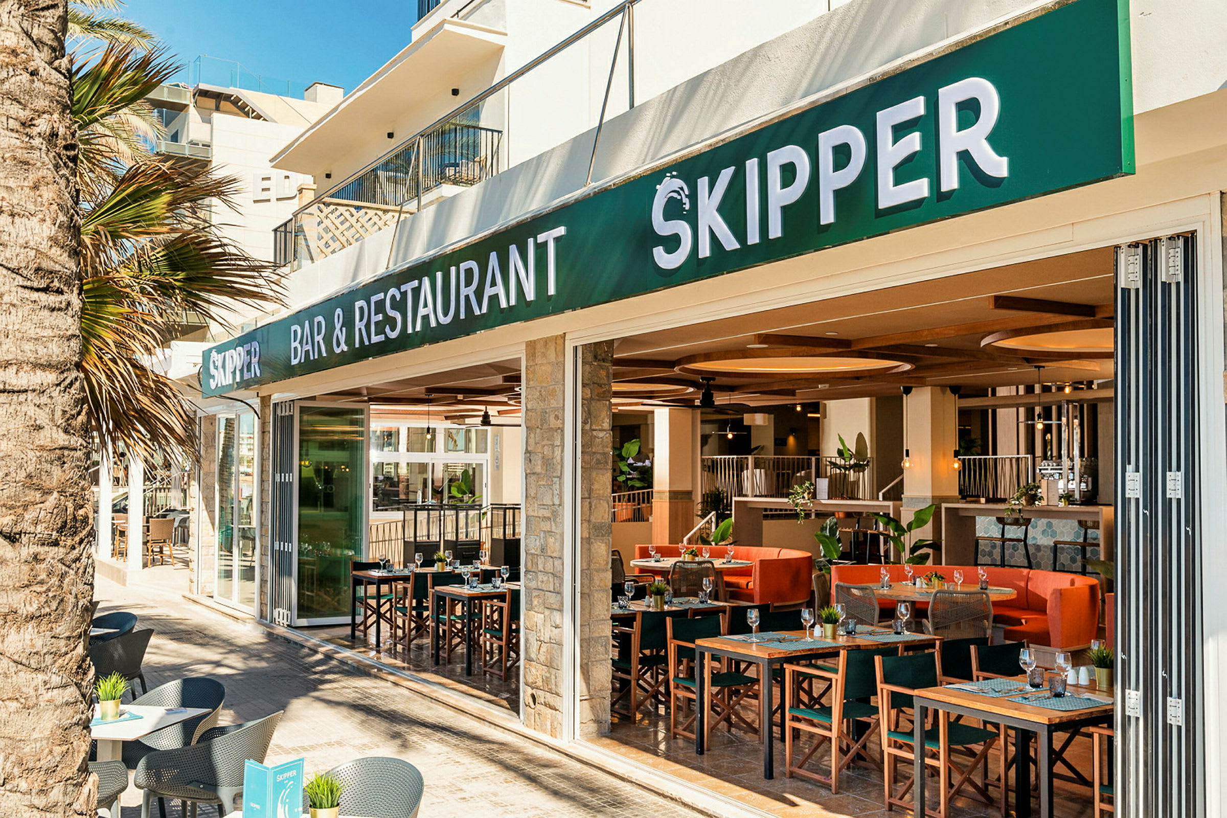 En restaurang och bar med namnet Skipper, utomhus sittplatser och interiör synlig. (AI-genererad text)