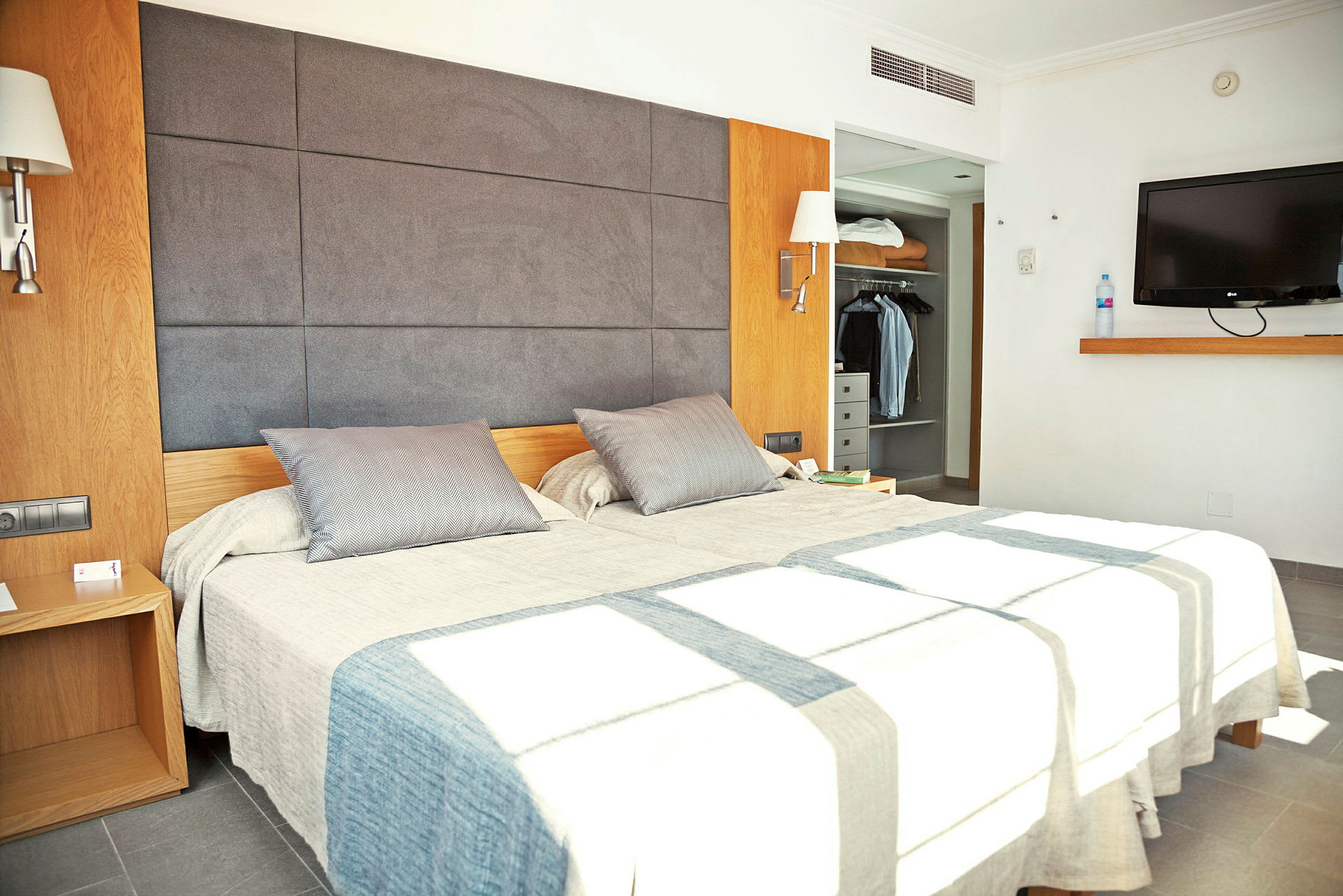 Bild som visar ett modernt hotellrum med en dubbelsäng, en garderob och en väggmonterad TV. (AI-genererad text)